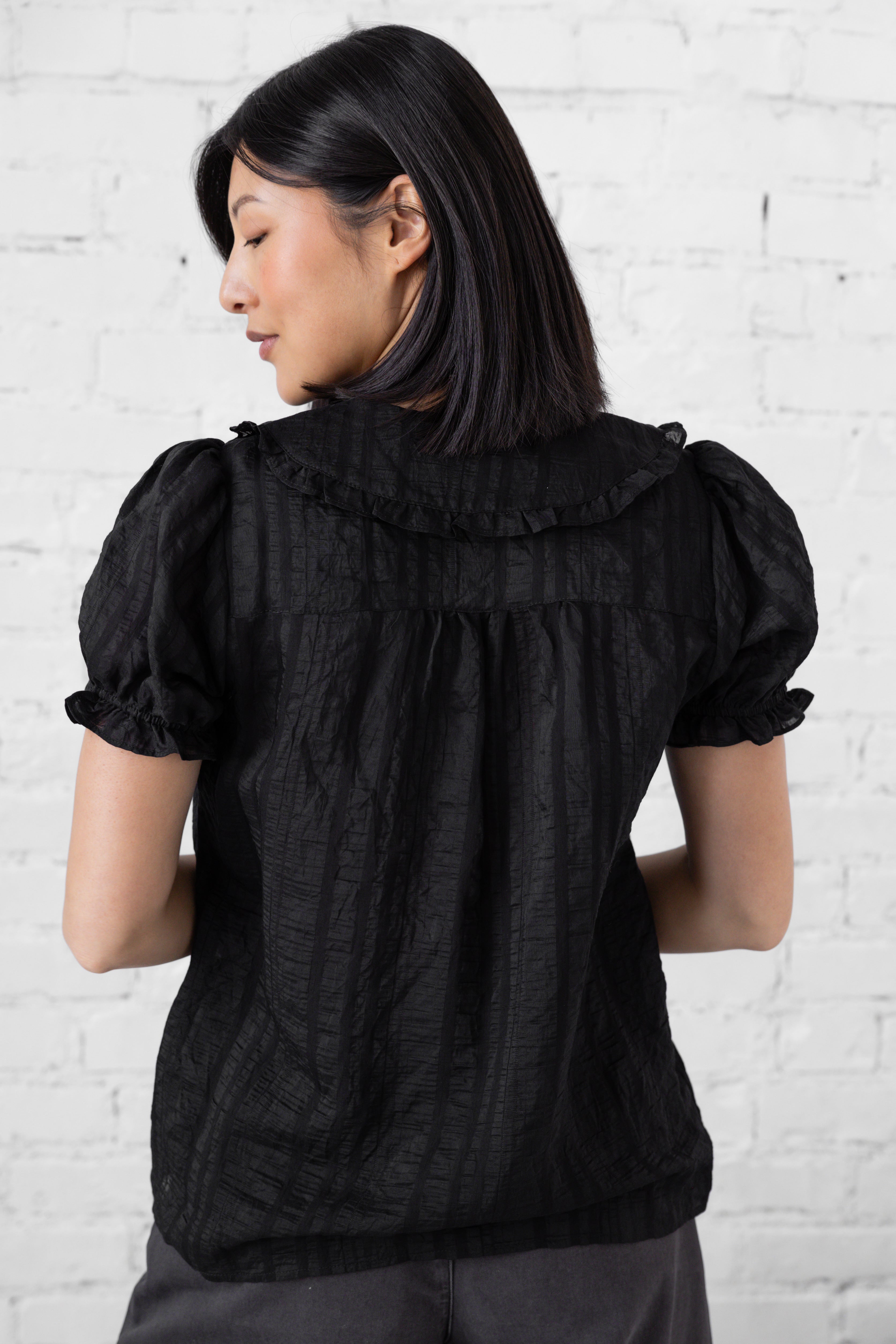 Model is wearing full length blouse with peter pan collar and button up.