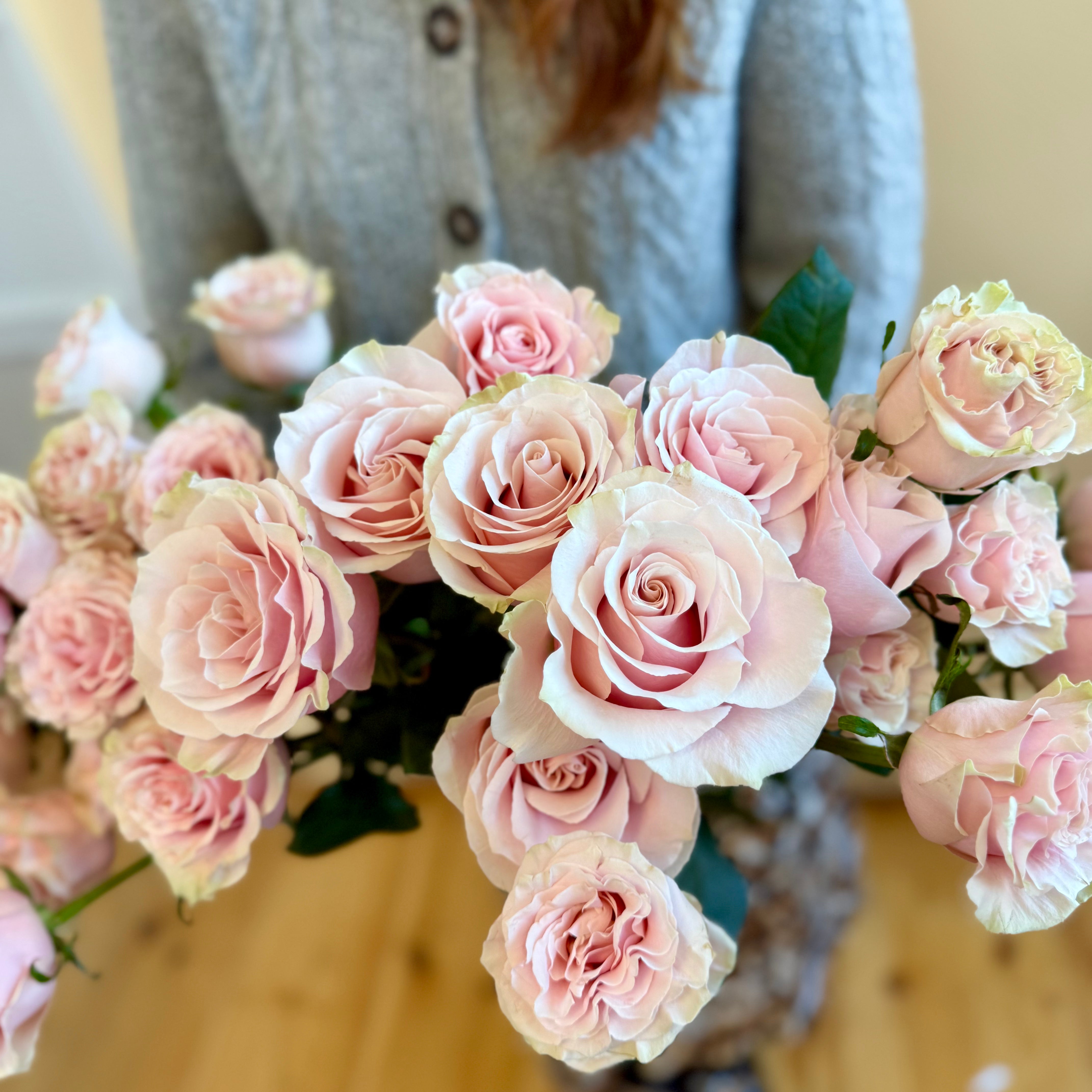 Model holding dozen blush roses.