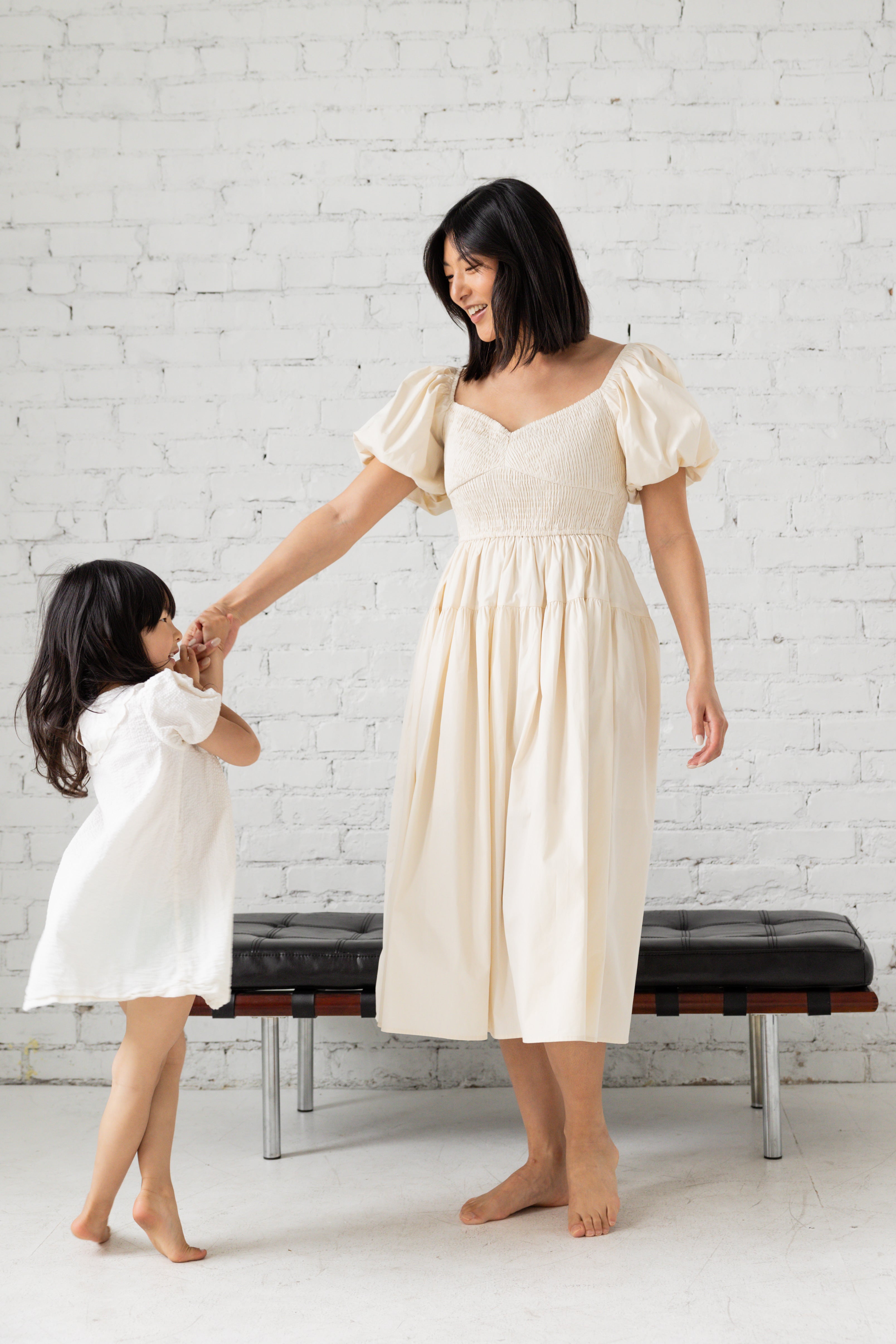Photo shoot of model in black midi dress with her children.