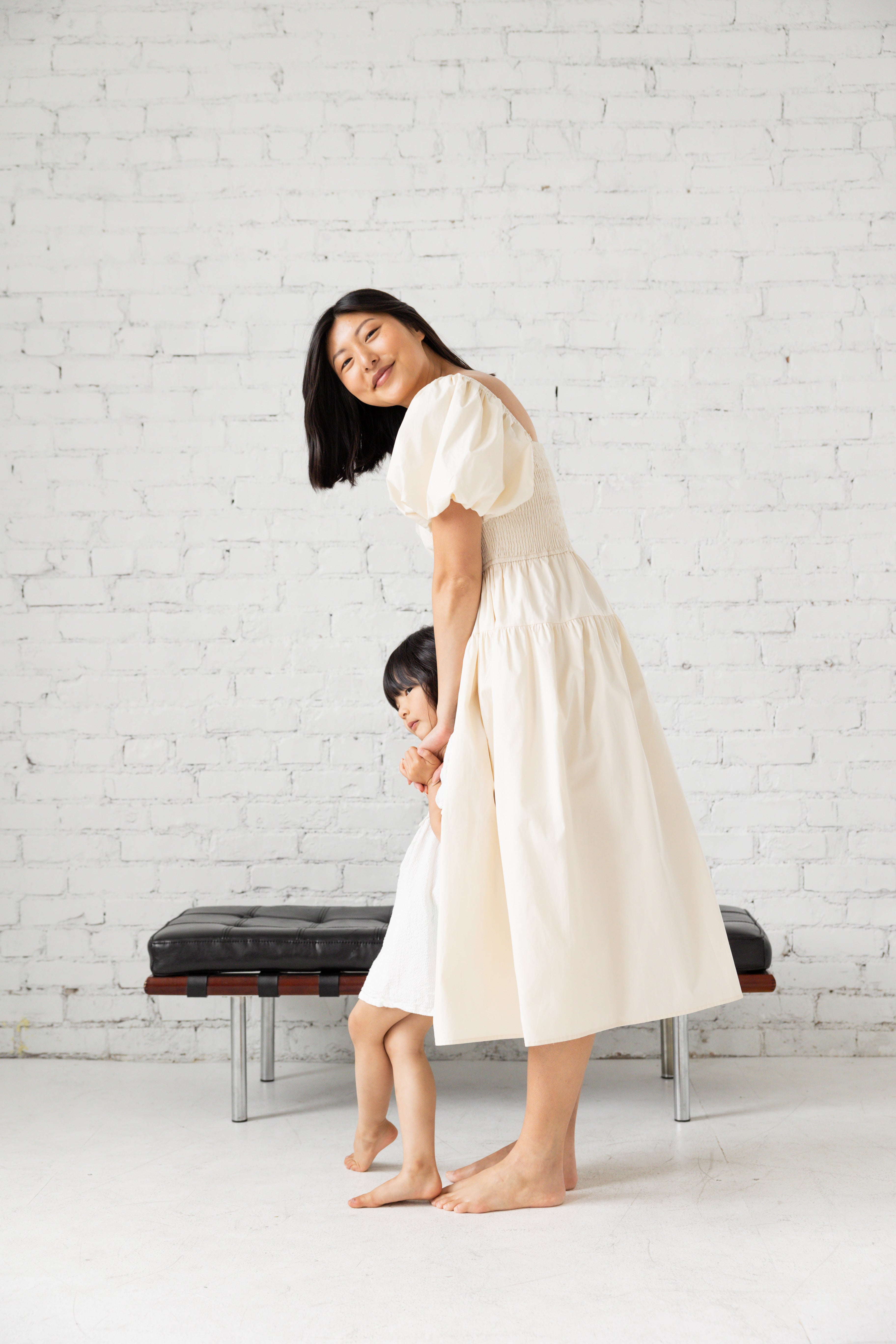 Photo shoot of model in black midi dress with her children.