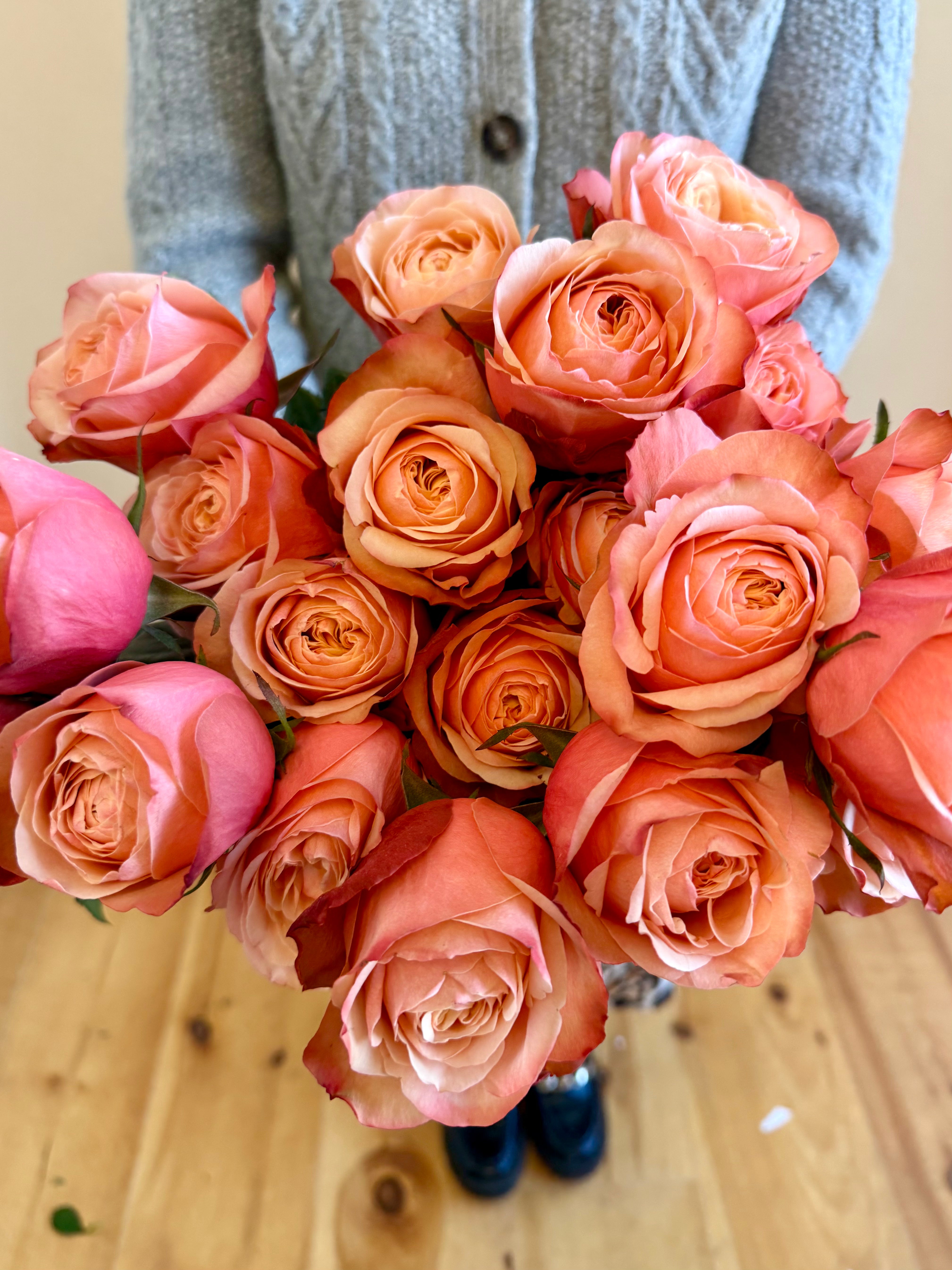 Woman holding a dozen sunset roses.