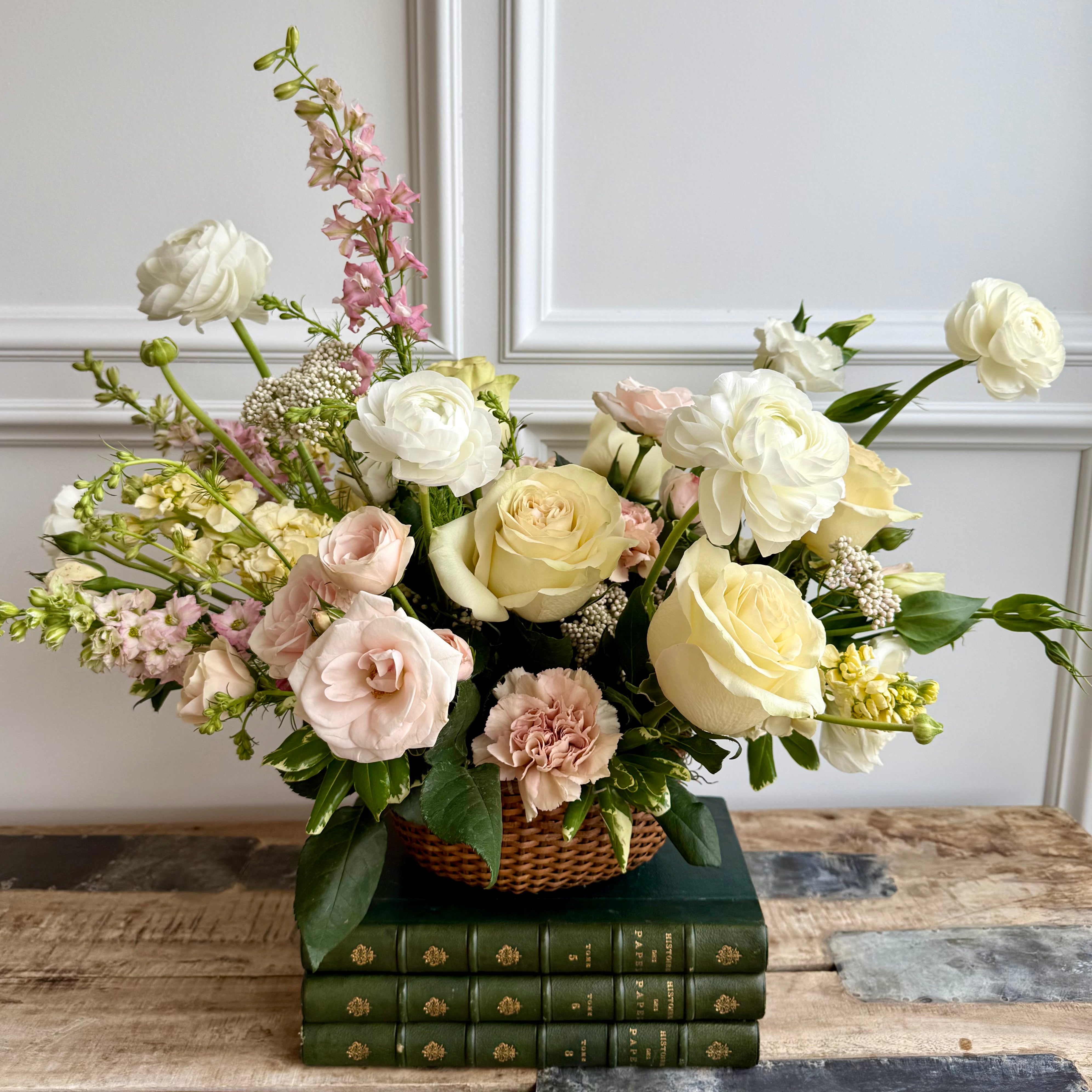 A soft and elegant floral arrangement in a woven basket