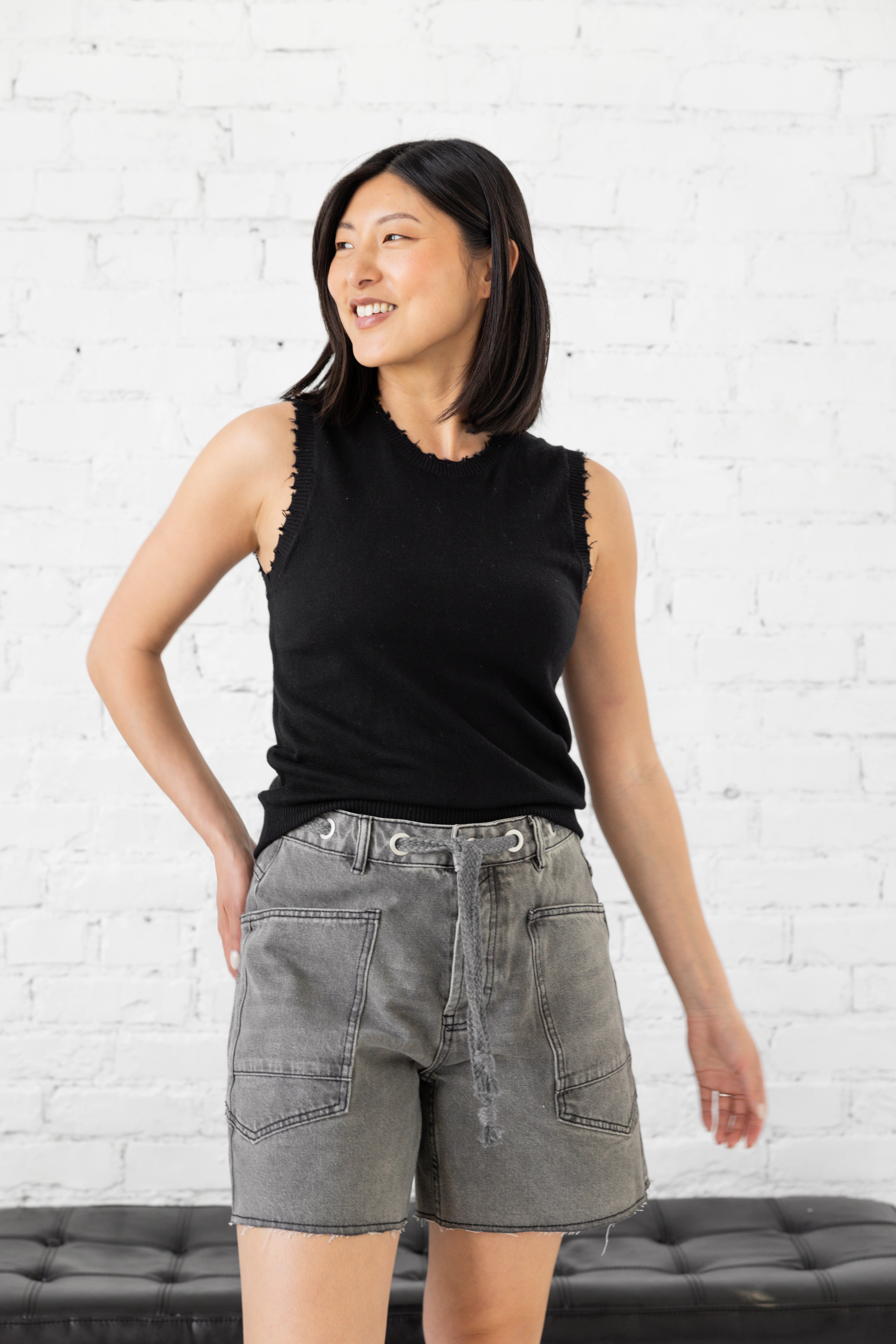 Model is wearing black frayed scoop neck tank top.
