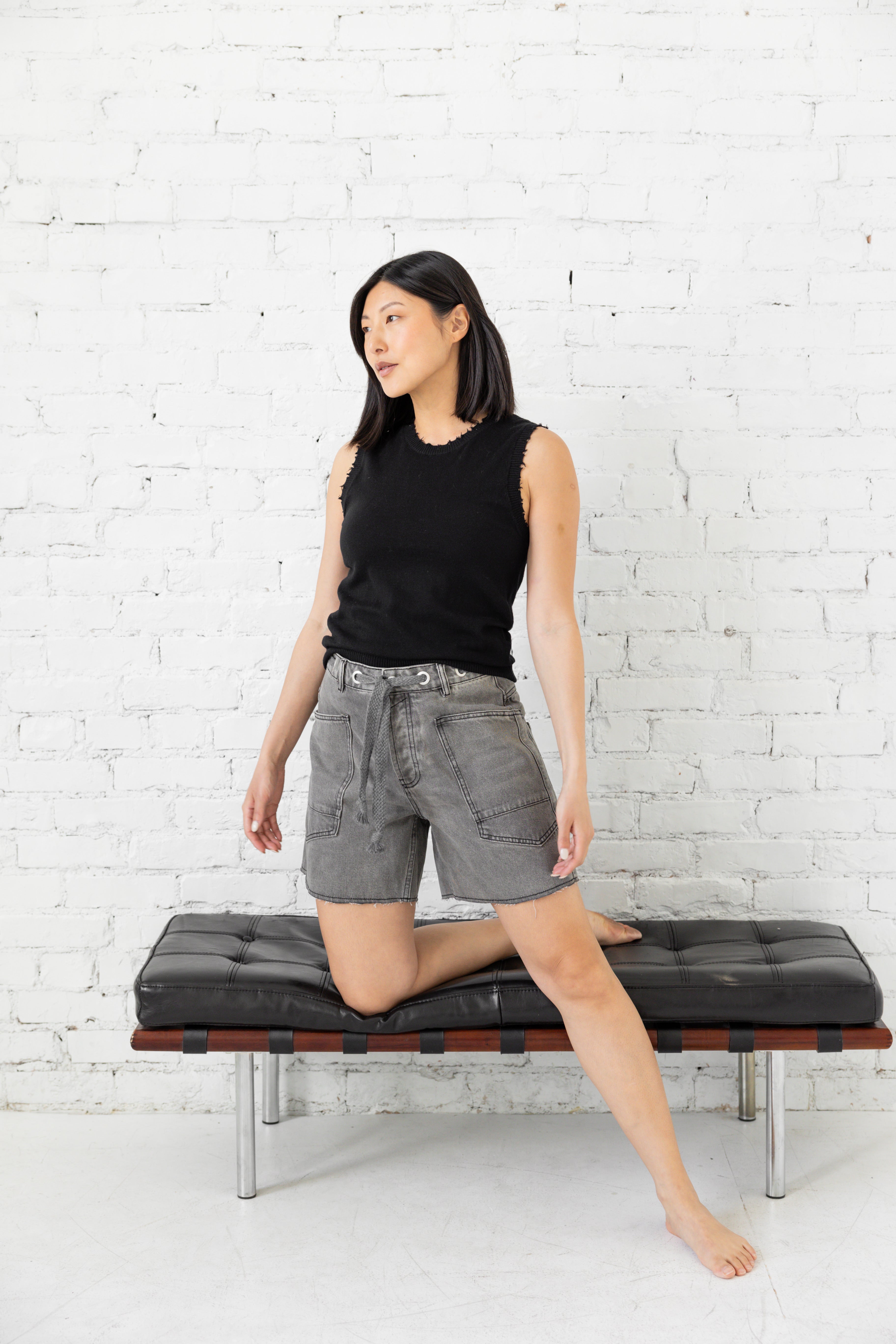 Model is wearing oversized high waist grey shorts with drawstring tie belt and large pockets.