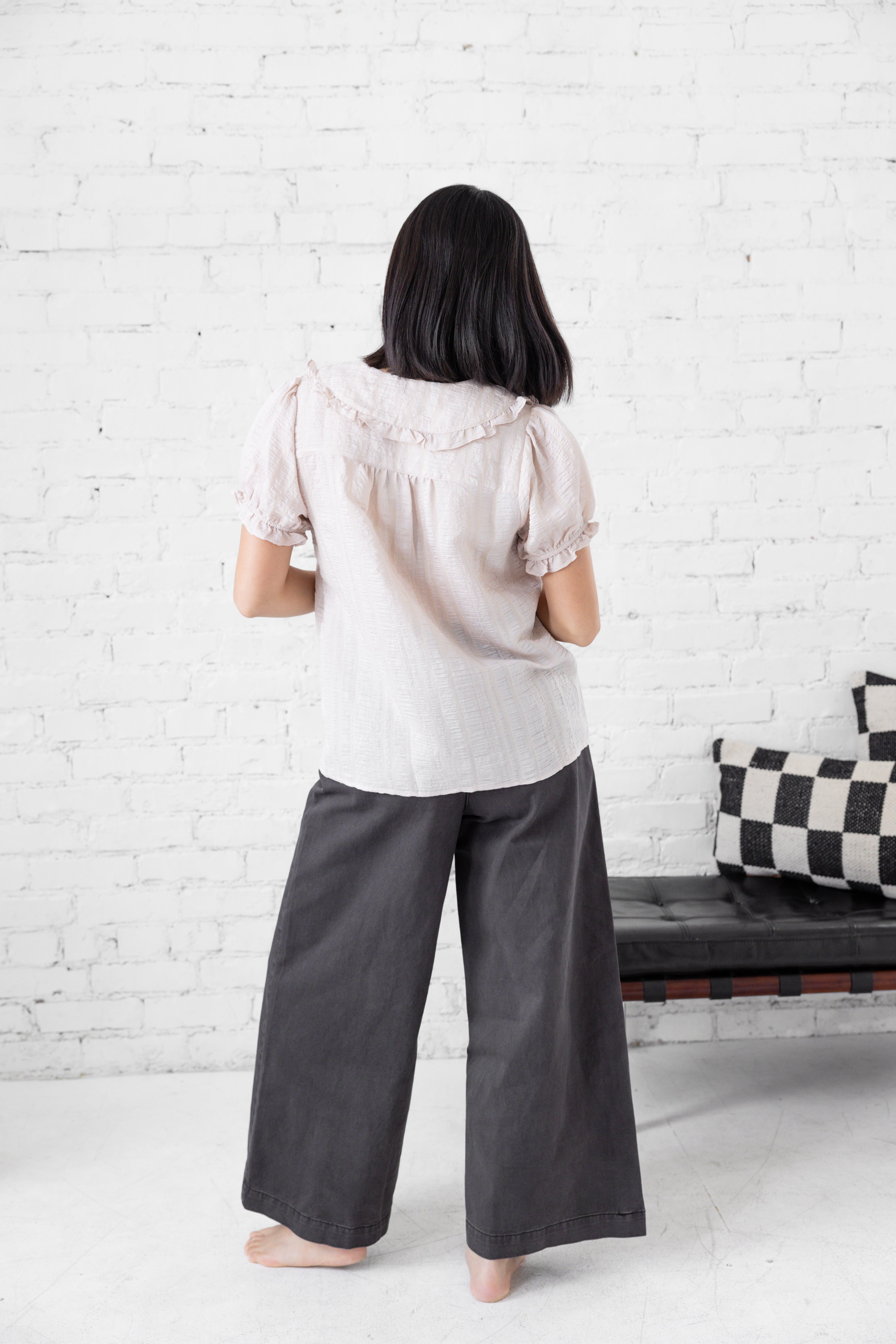 Model is wearing full length blouse with peter pan collar and button up.