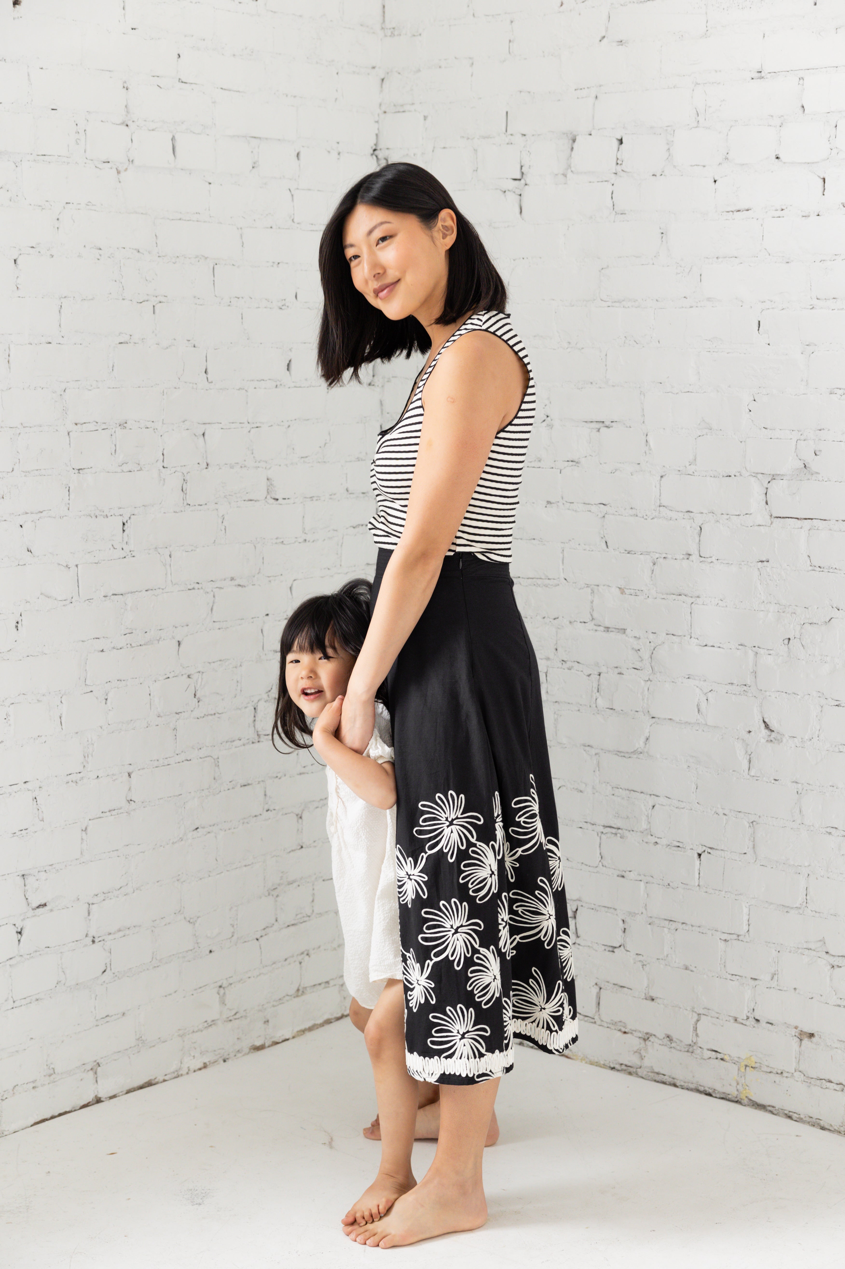 Model is wearing a midi black skirt with floral embroidery.