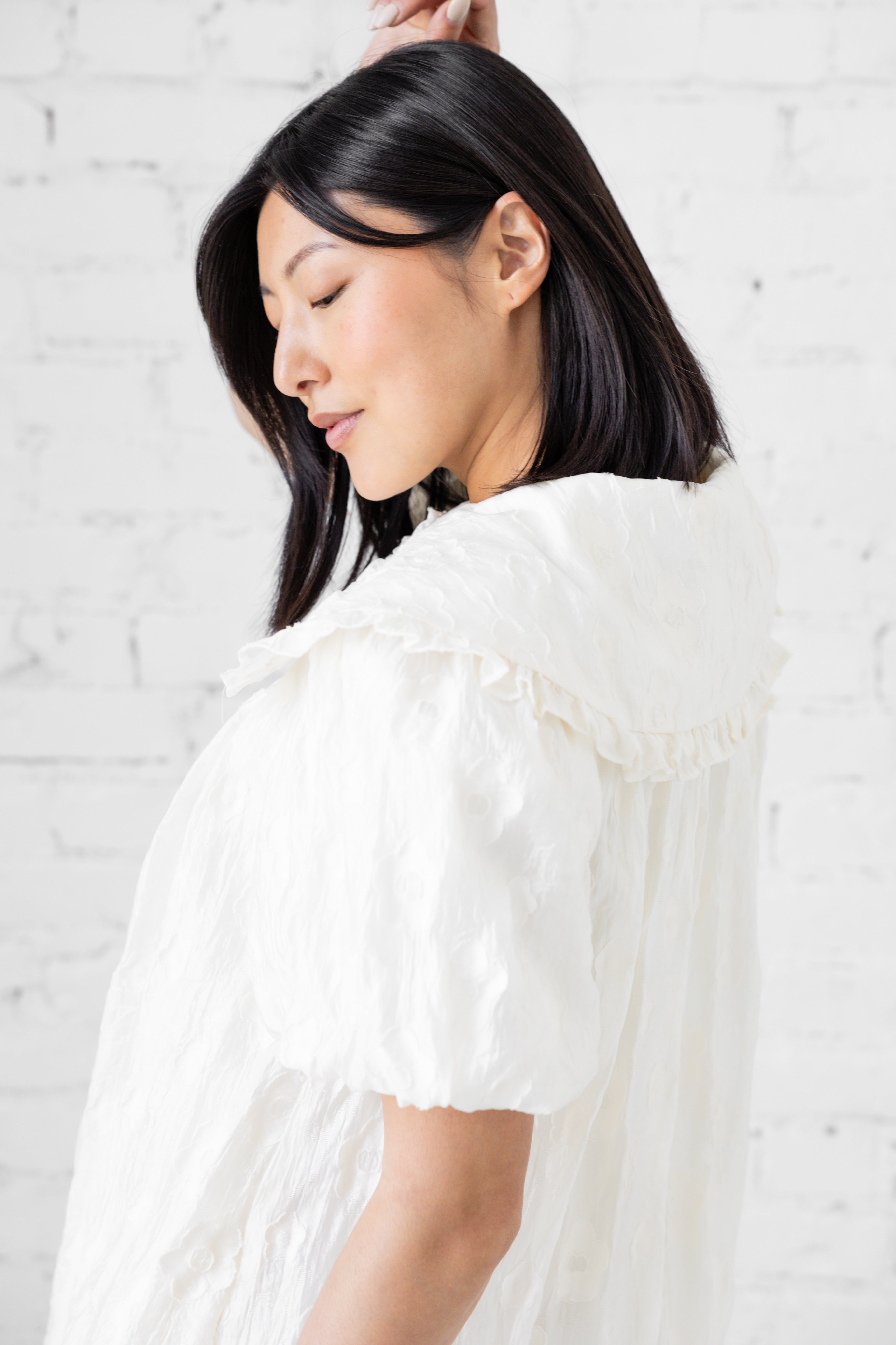 Model wearing white mini dress with puffer sleeves and peter pan collar.
