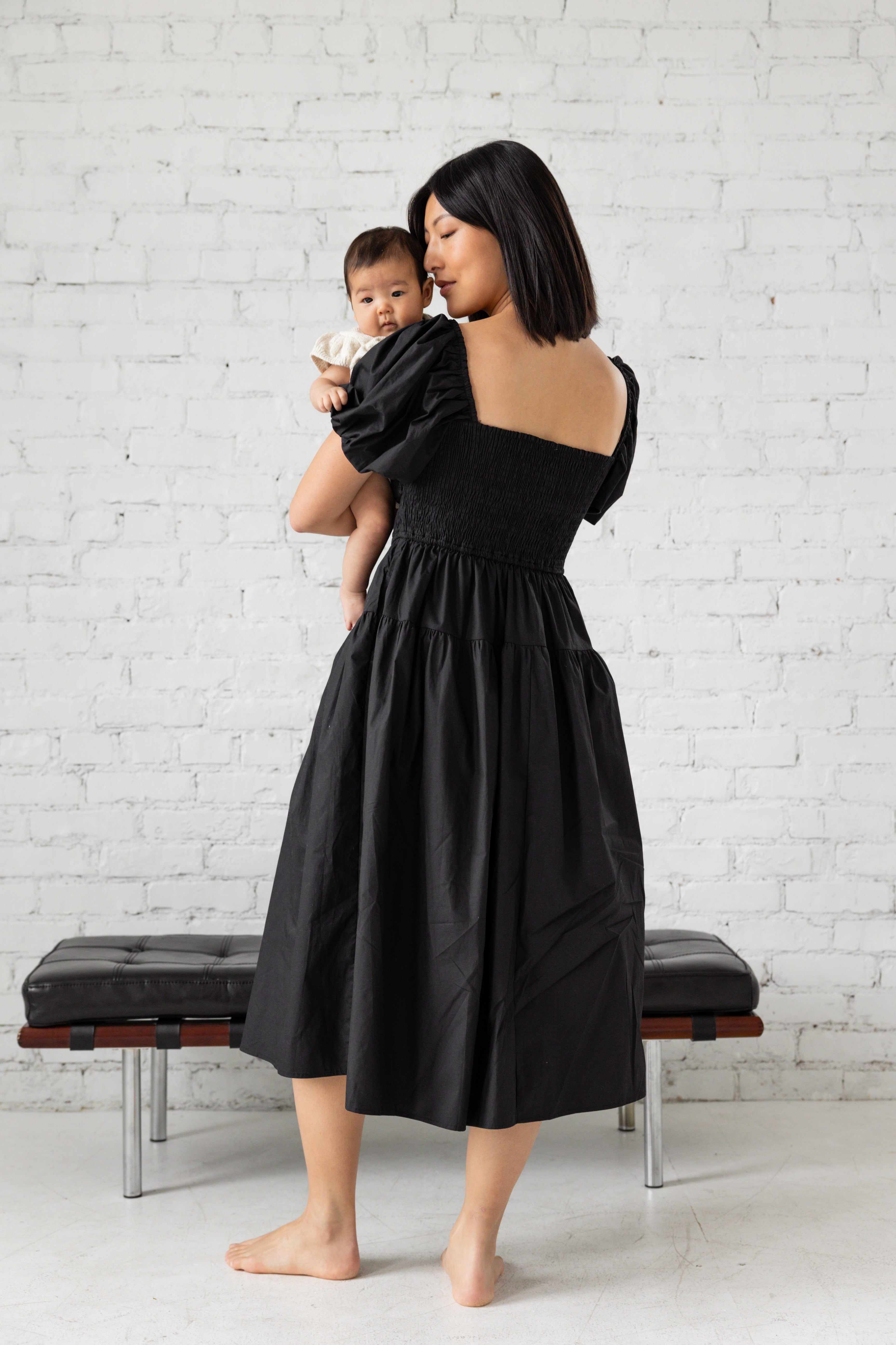 Photo shoot of model in black midi dress with her children.