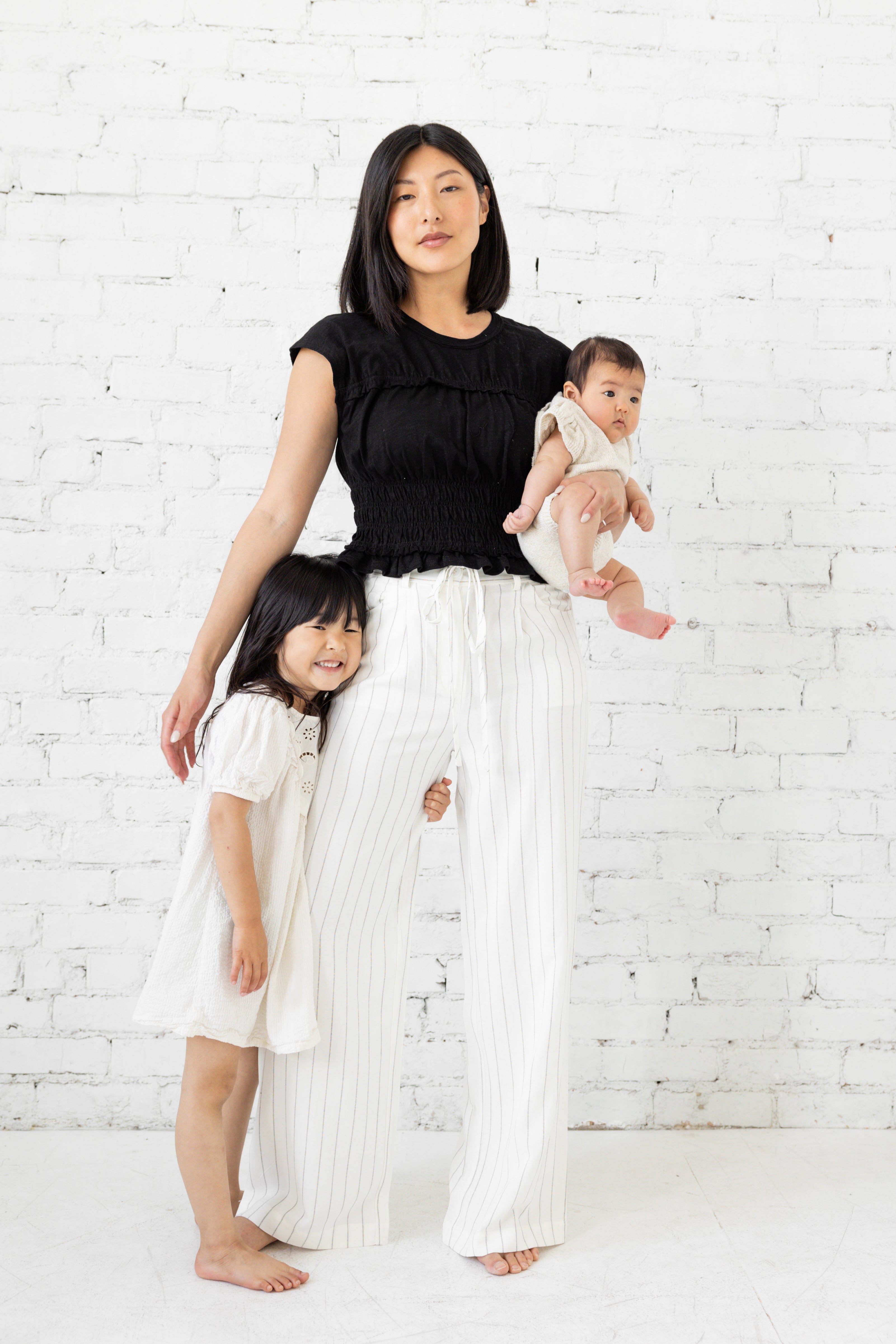 Model is wearing a white striped pant with tie waist belt.