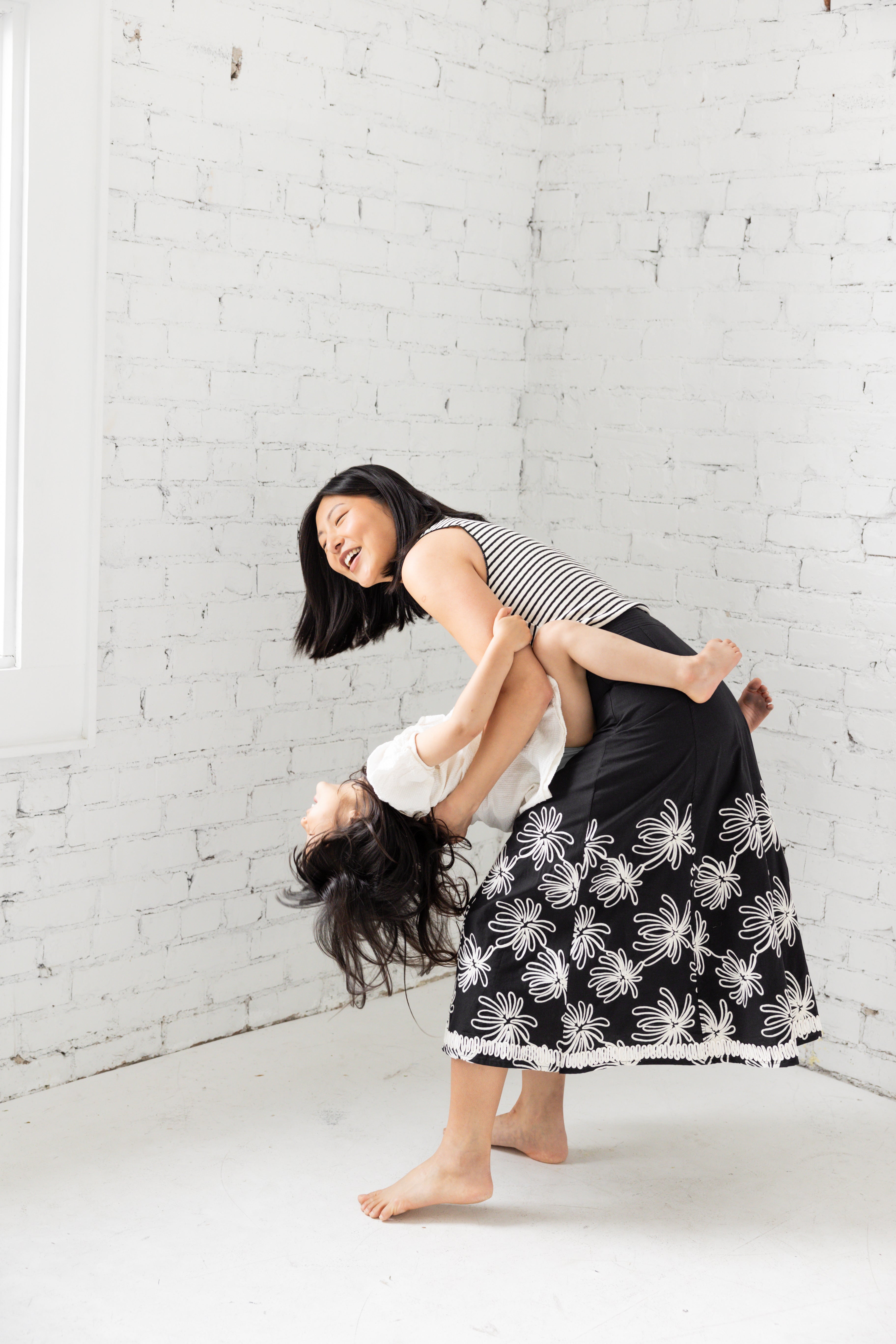 Model is wearing a midi black skirt with floral embroidery.