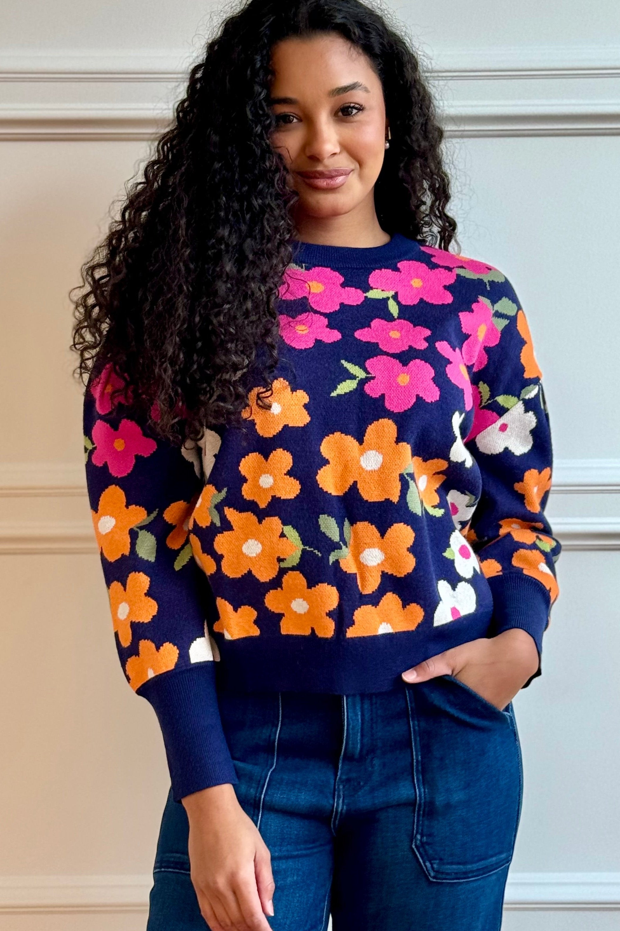 Woman standing wearing floral sweater. 