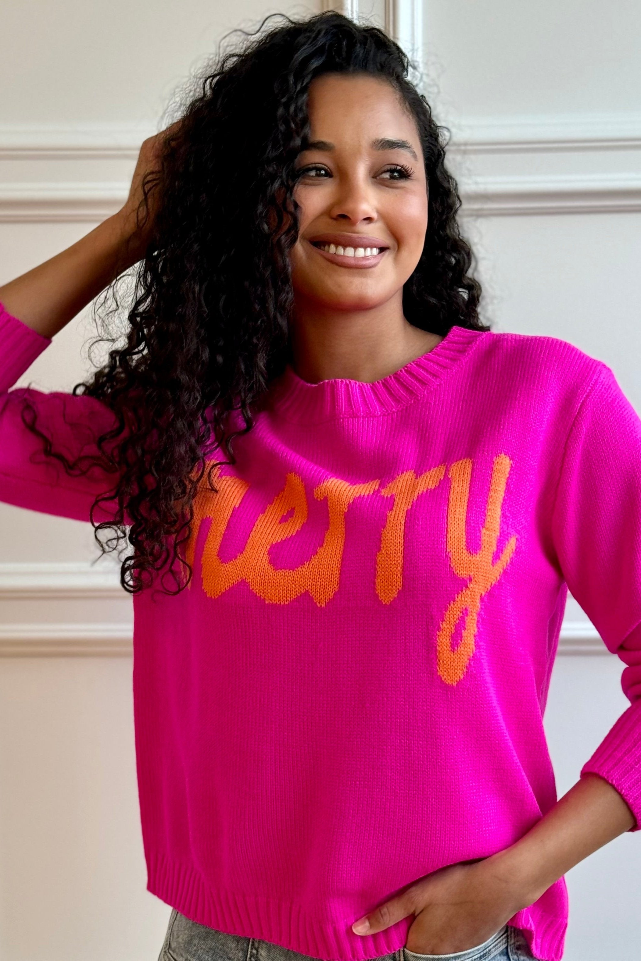 Woman looking away wearing a pink sweater. 