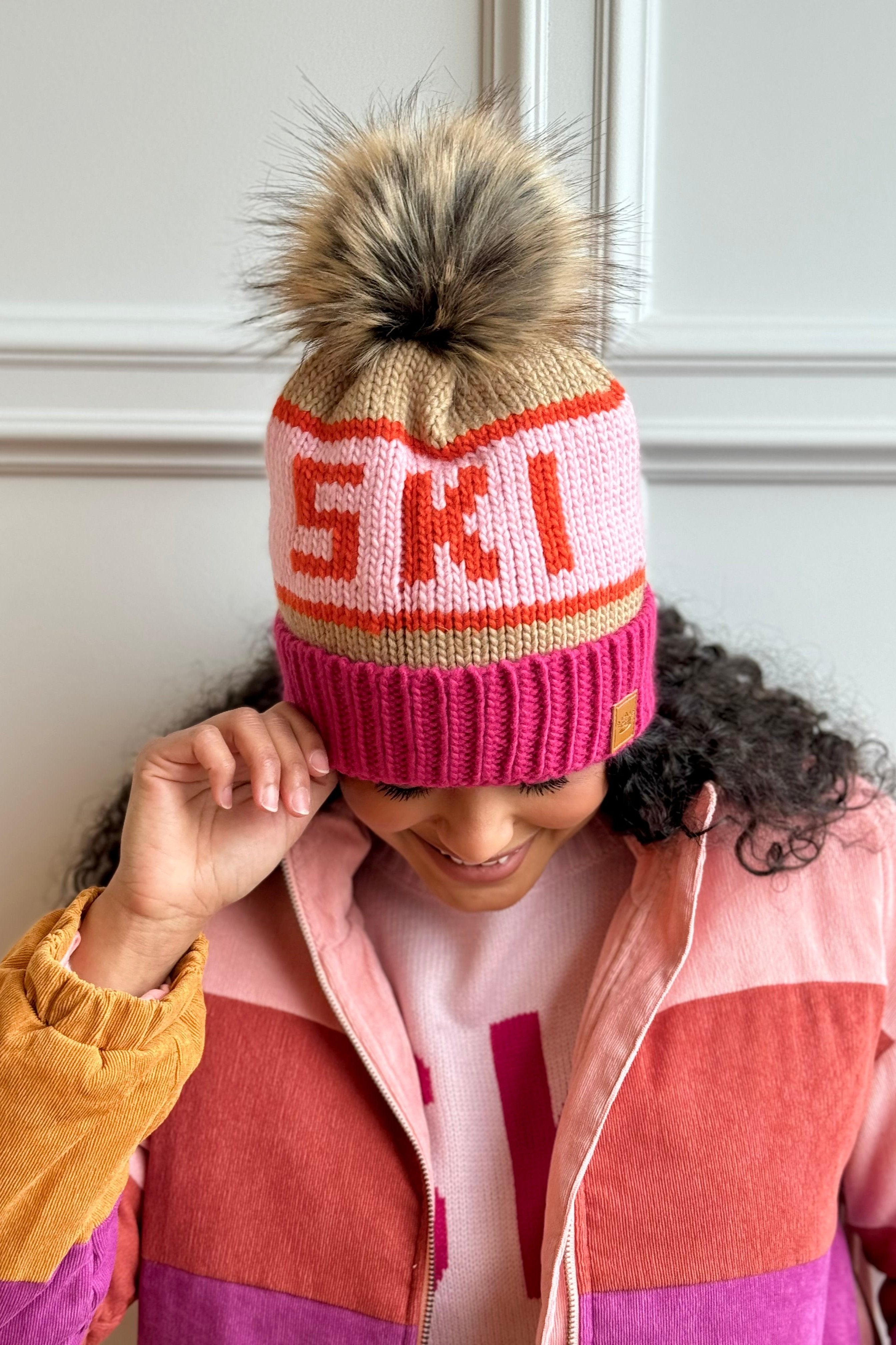 Woman looking down holding a ski pom hat