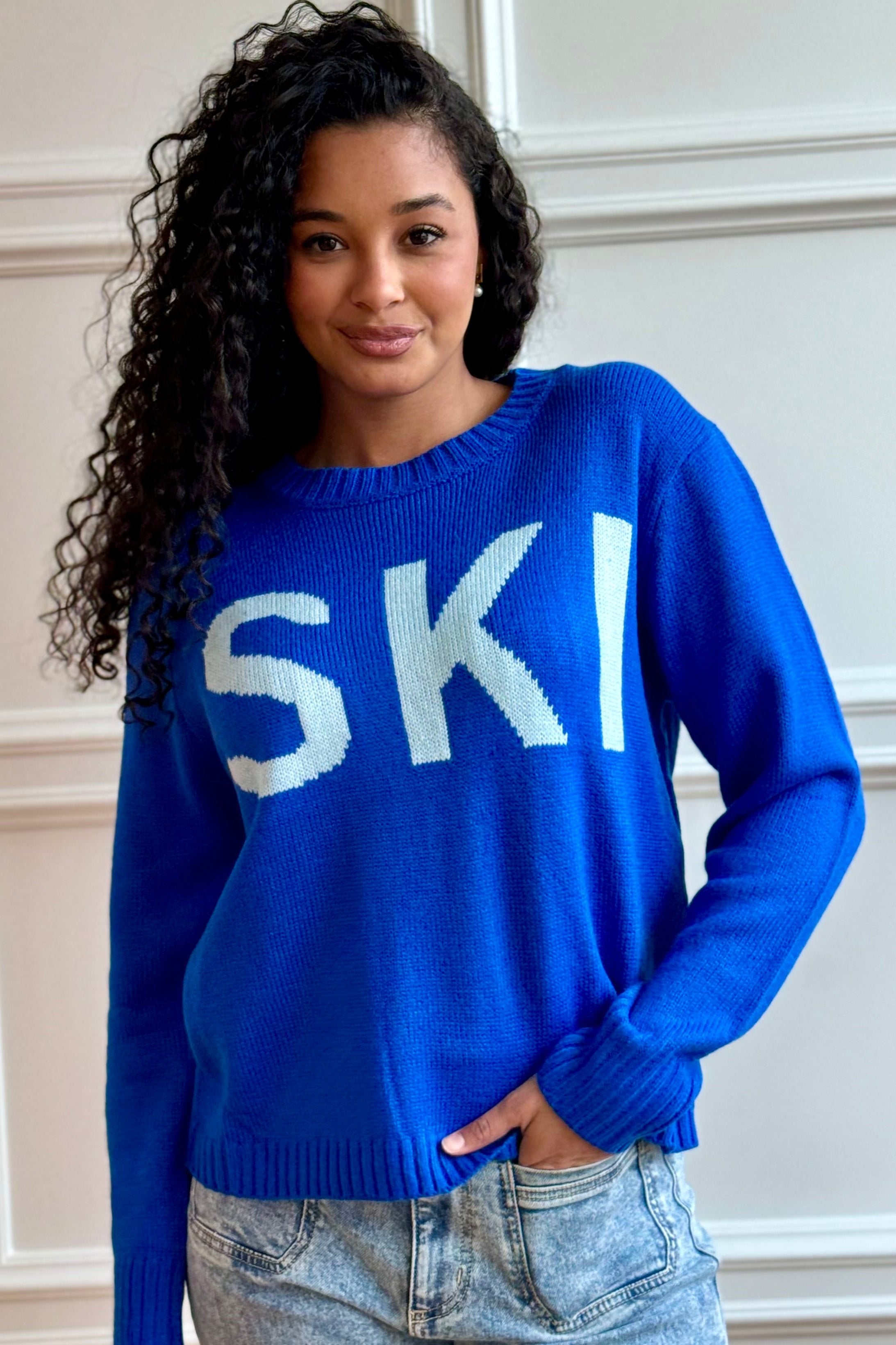 Woman wearing ski sweater with hand in pocket.