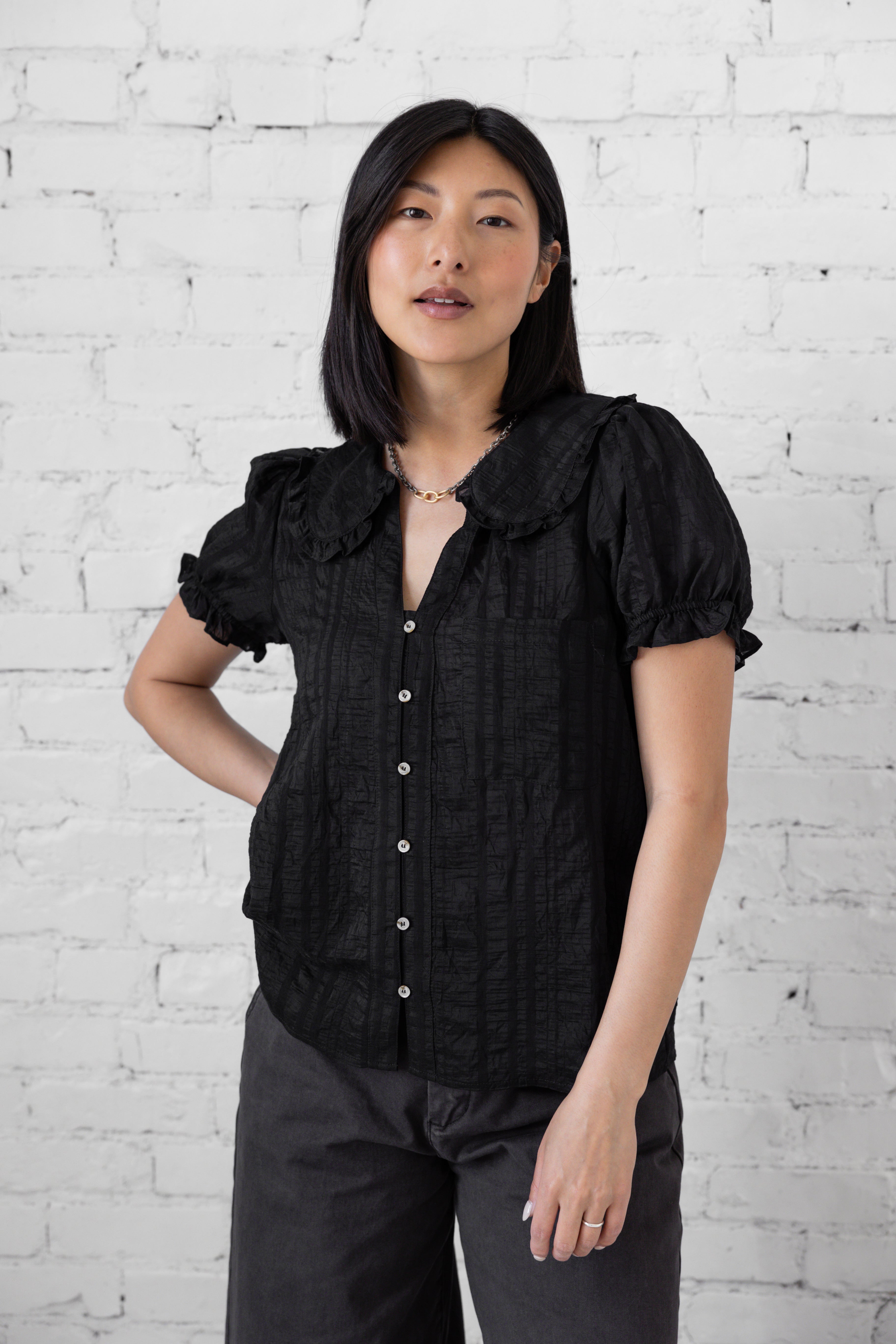 Model is wearing full length blouse with peter pan collar and button up. 