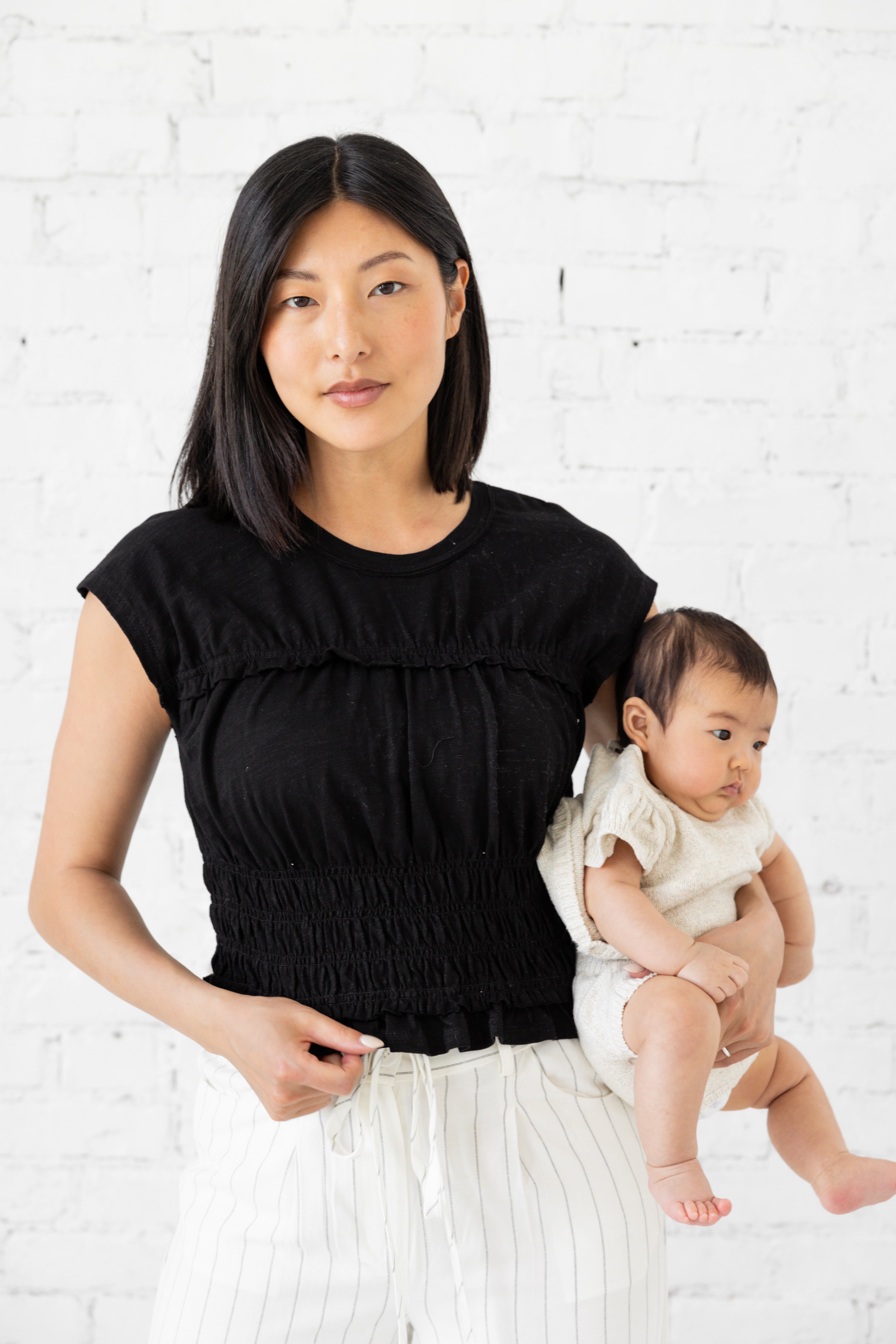 Model is wearing black full length fitted short-sleeve blouse.