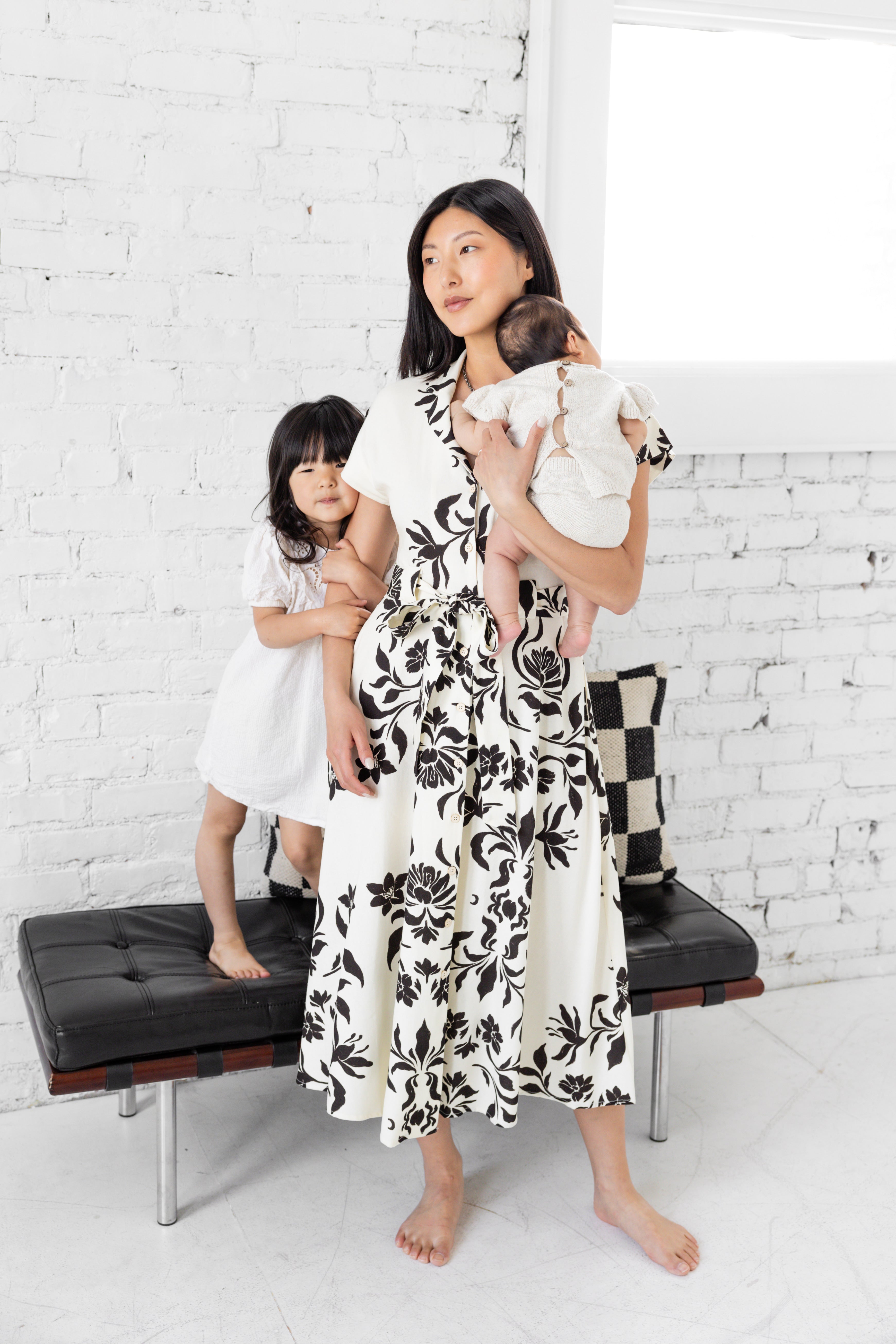 Model is wearing midi collared dress with belt with her family. 
