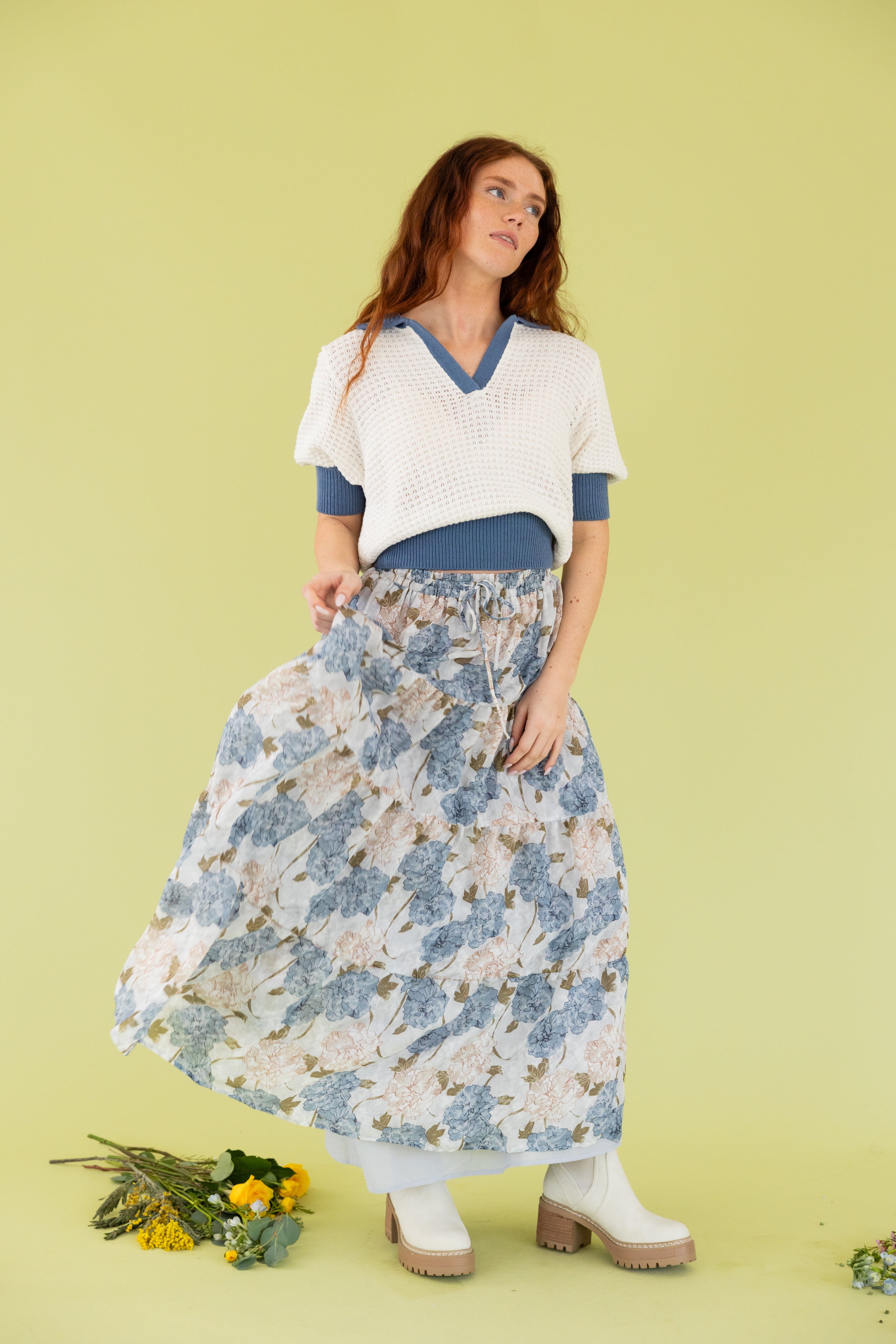 Model is wearing a knit sweater short sleeve top with midi floral blue and white skirt. 