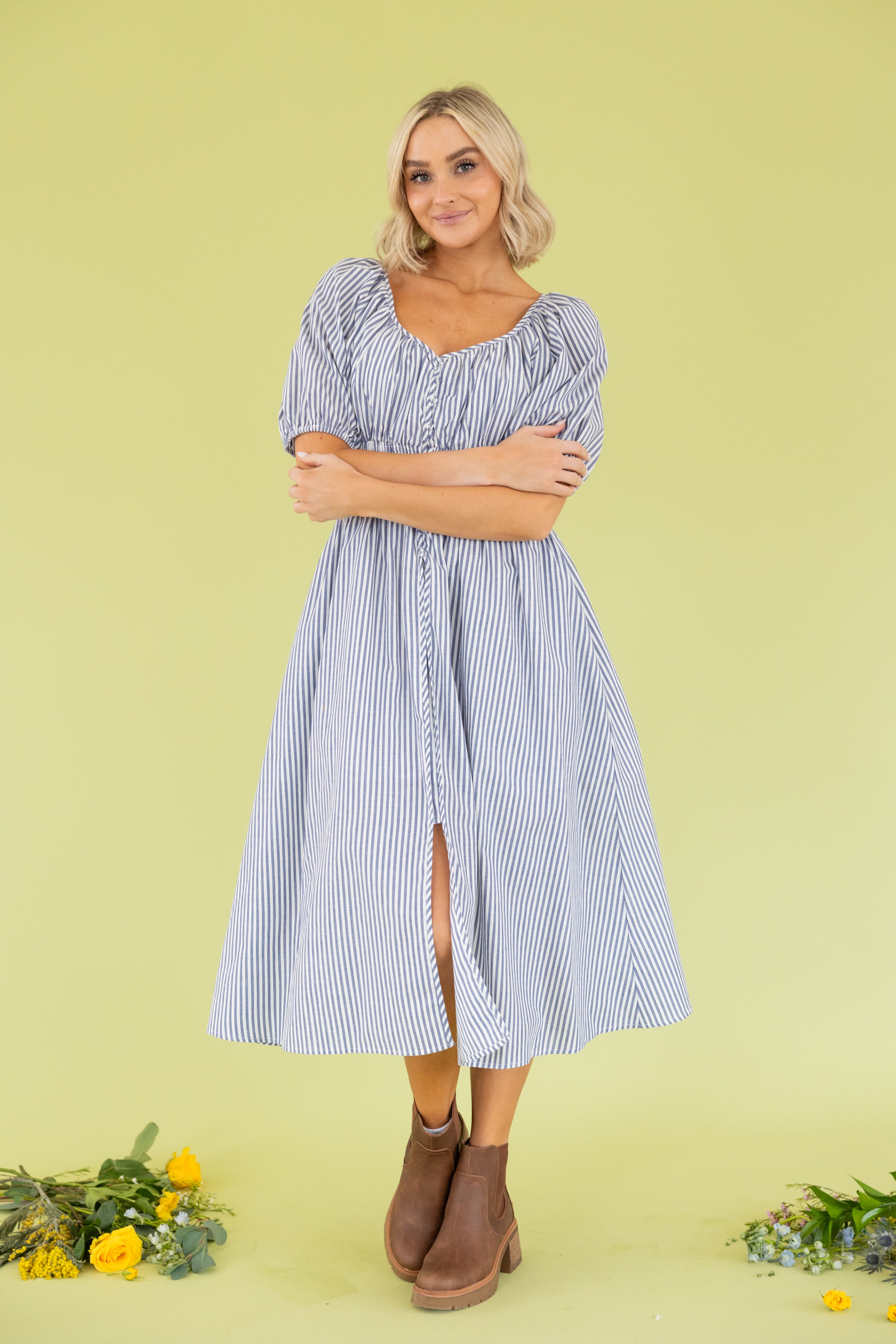 Model is wearing midi blue and white dress with sweetheart neckline. 