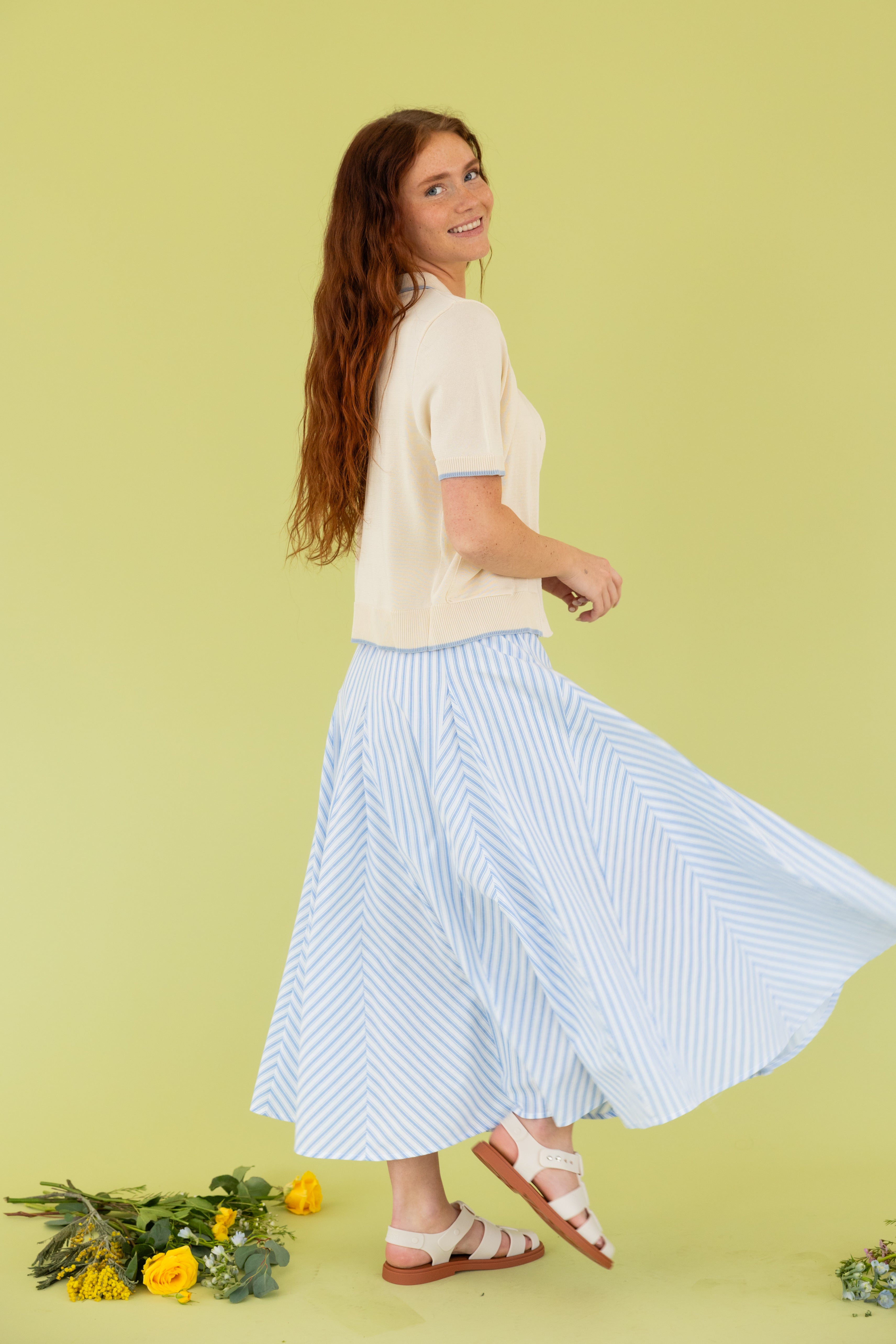 Model is wearing a short sleeve cardigan and skirt. 