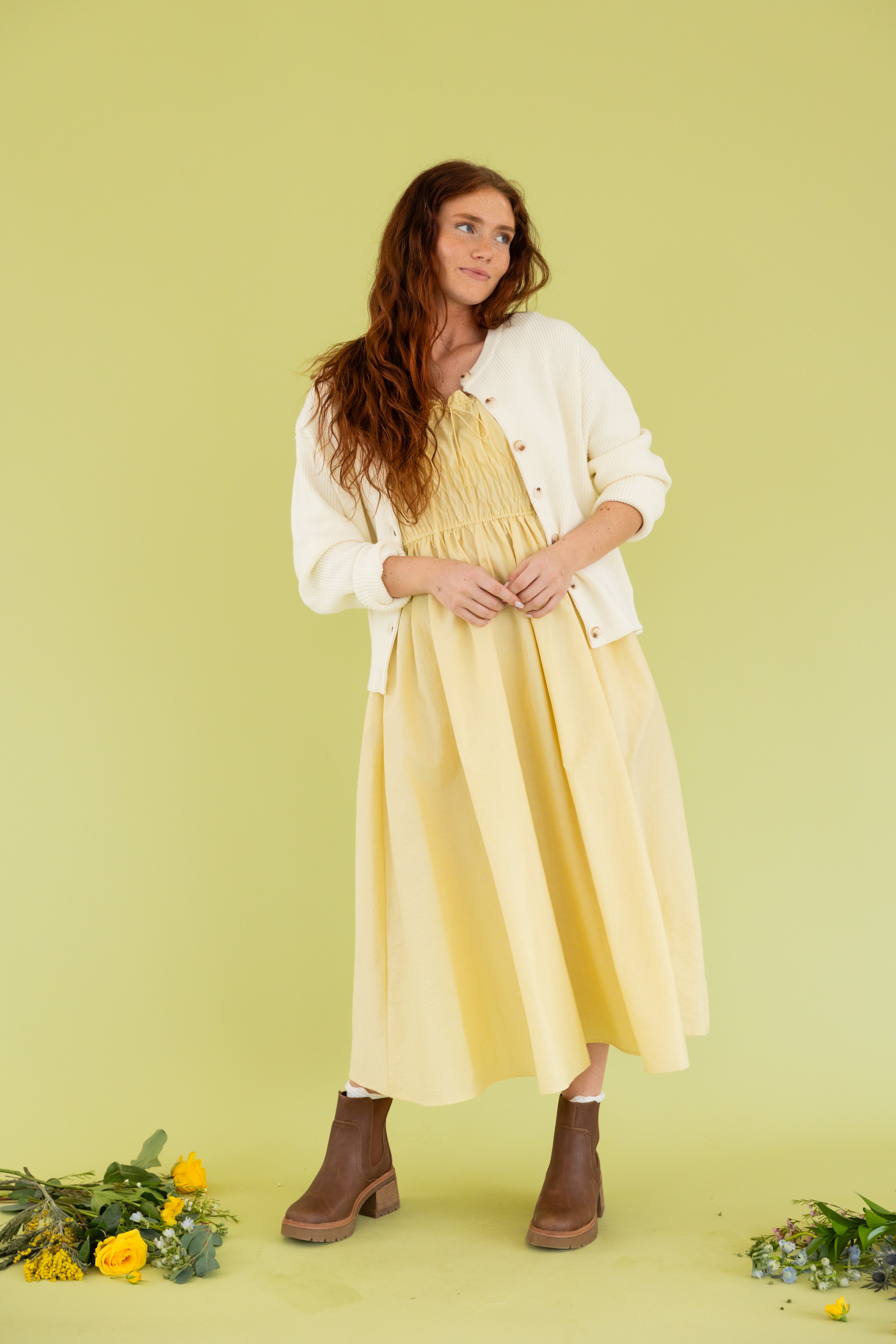 Model is wearing a yellow midi dress and cream cardigan. 