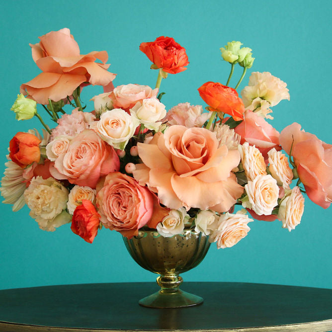 Coral floral vase arrangement in gold vase.