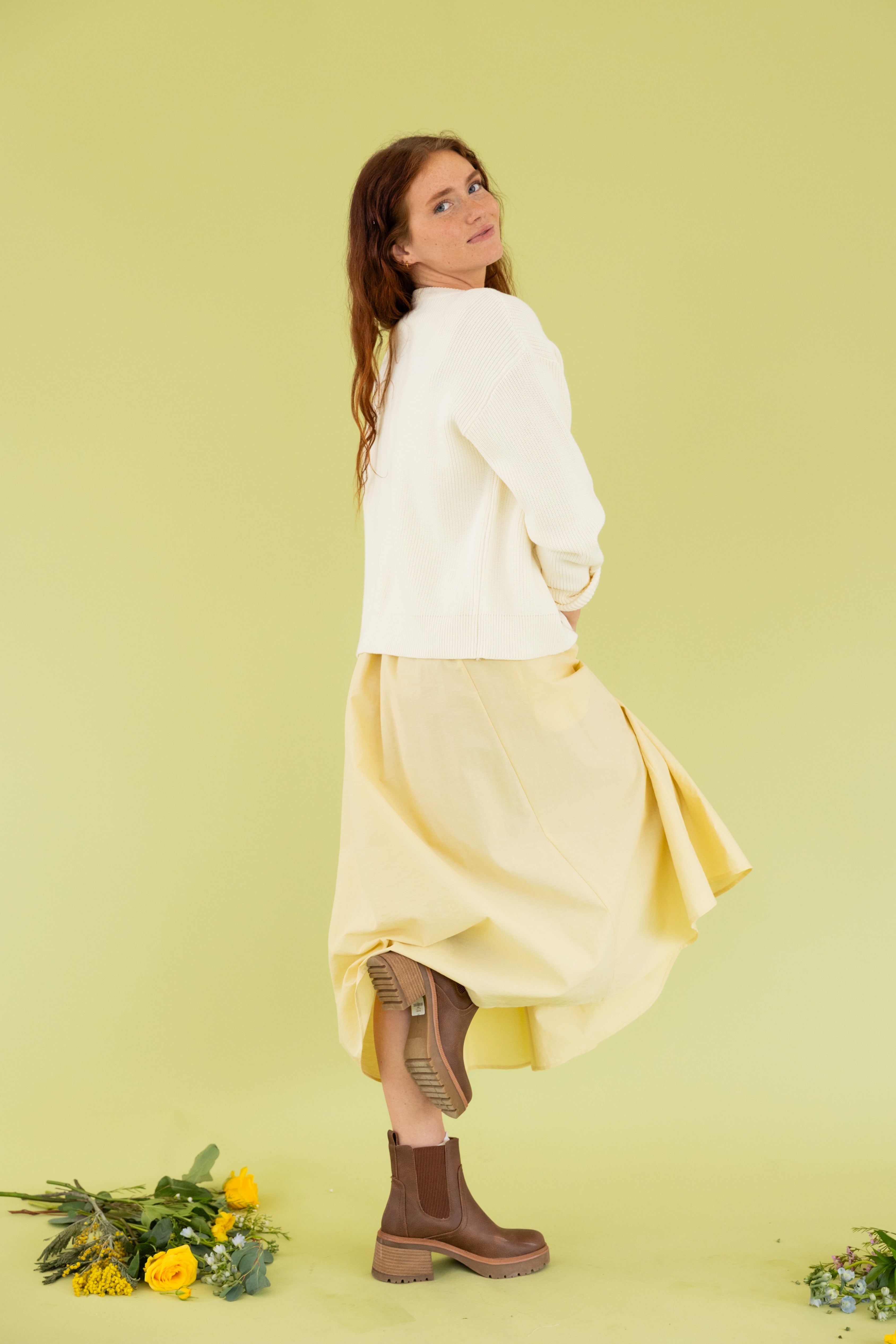 Model is wearing a yellow midi dress and cream cardigan. 