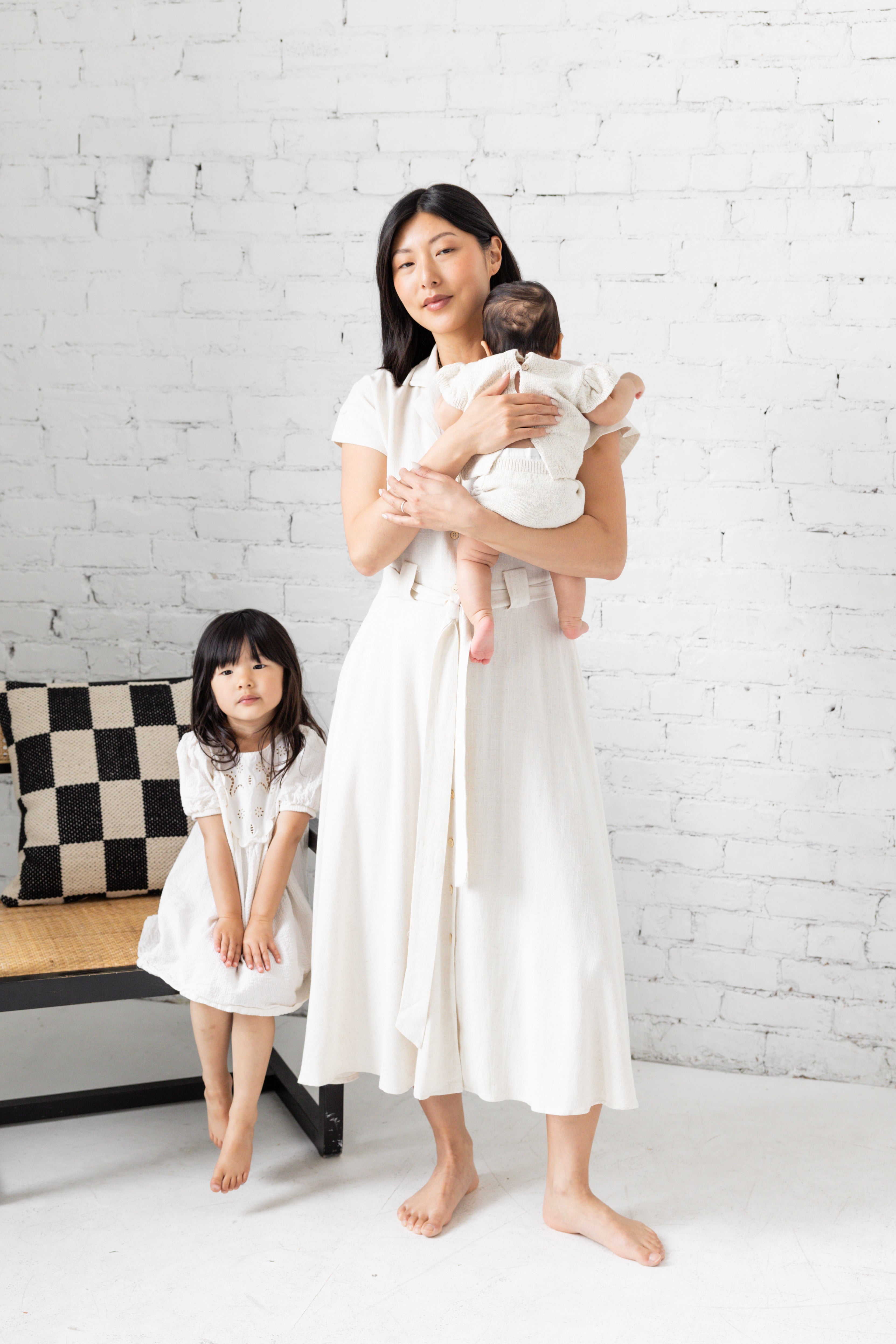 Model is wearing midi collared dress with belt with her family. 
