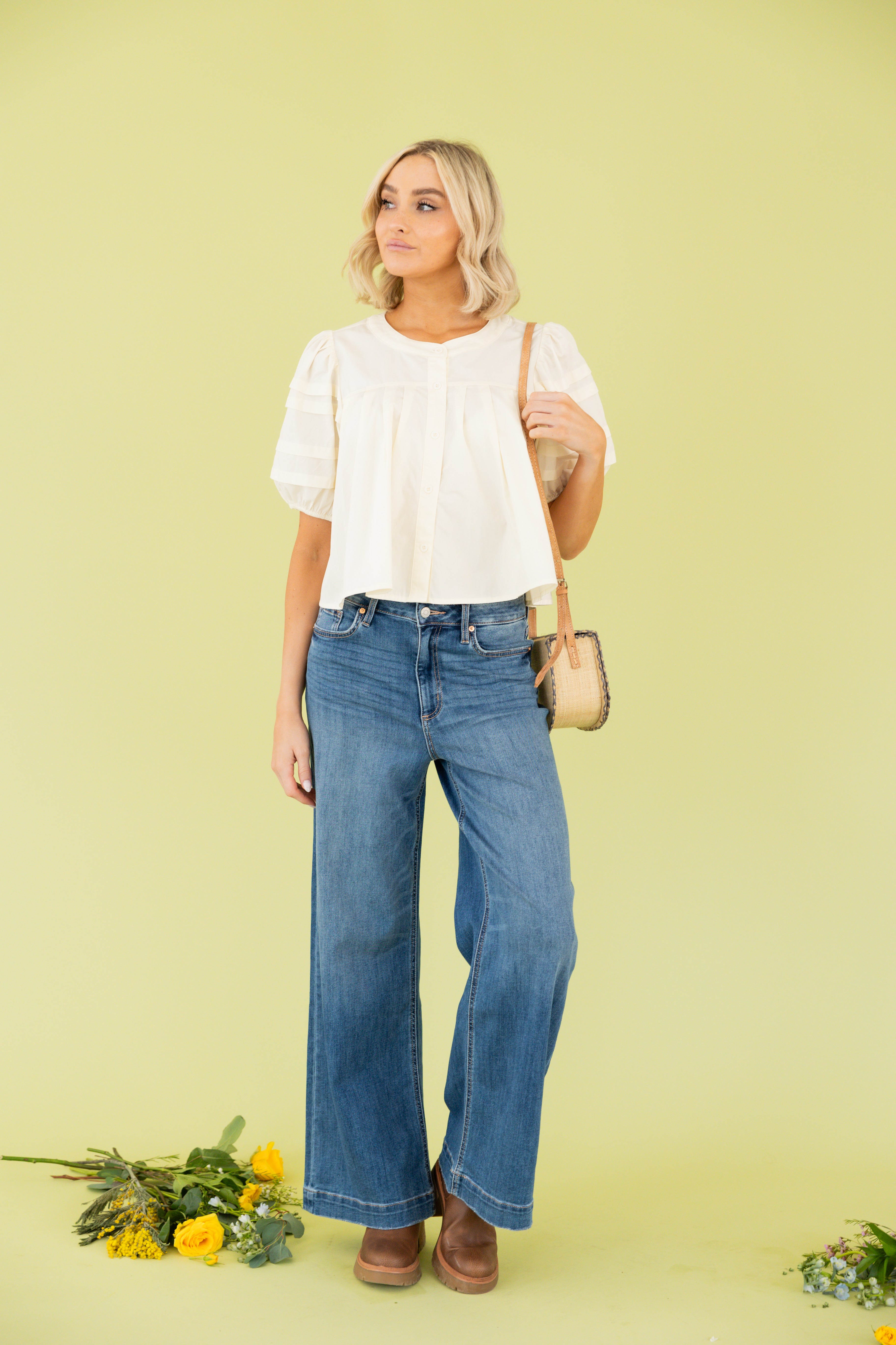 Model is wearing white blouse with wide leg dark wash jean 