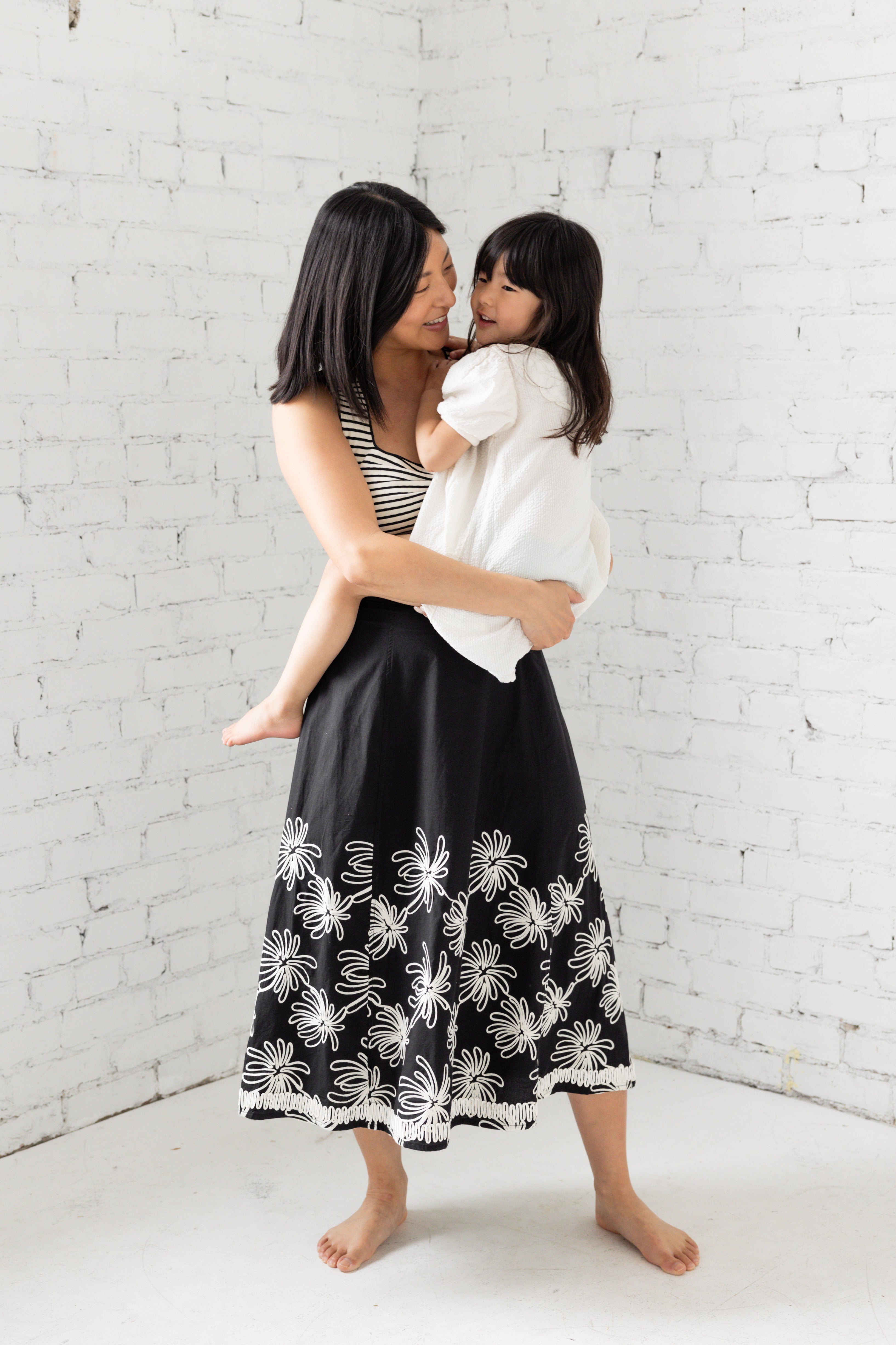 Model is wearing a midi black skirt with floral embroidery. 