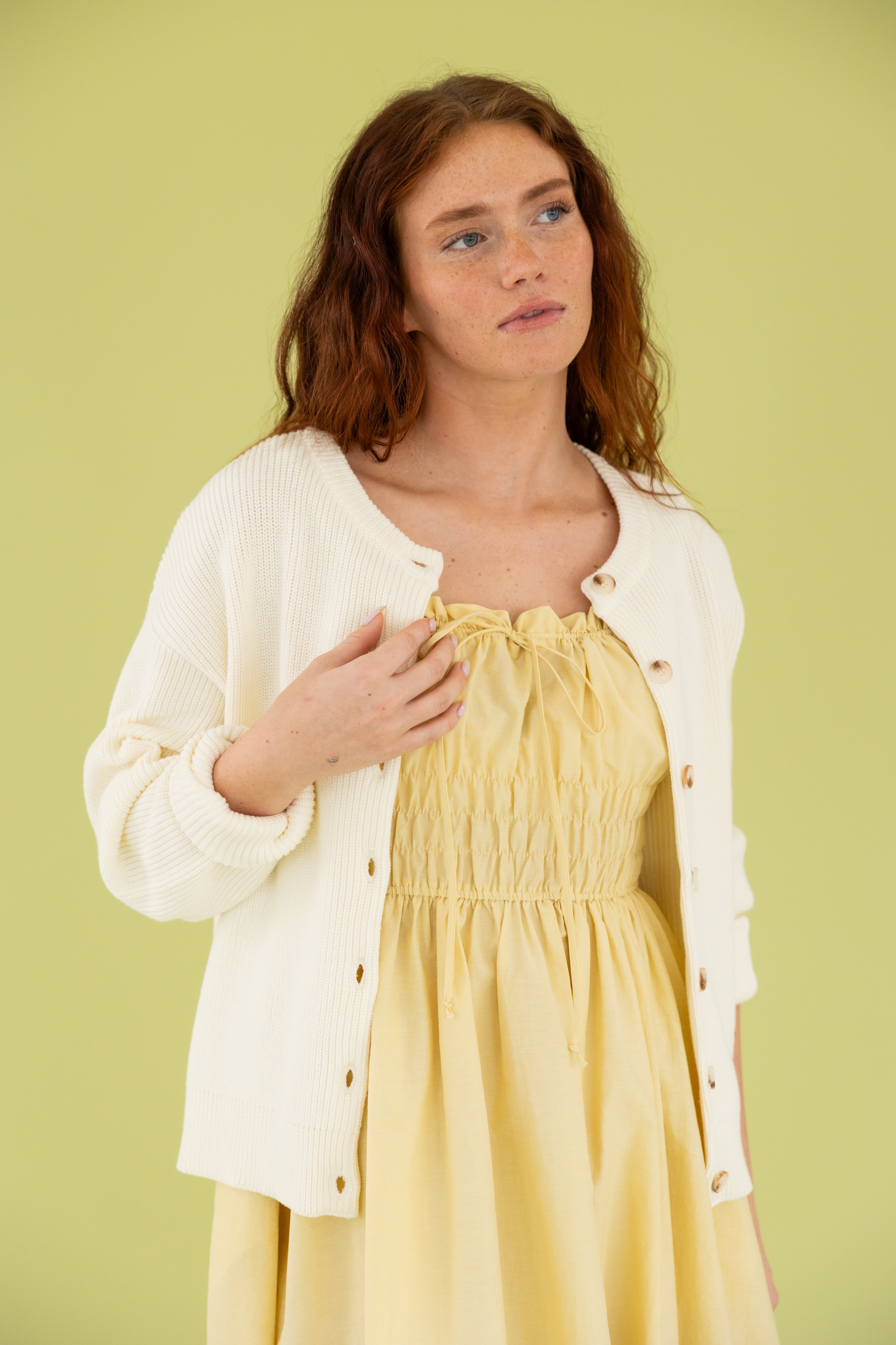 Model is wearing a yellow midi dress and cream cardigan. 