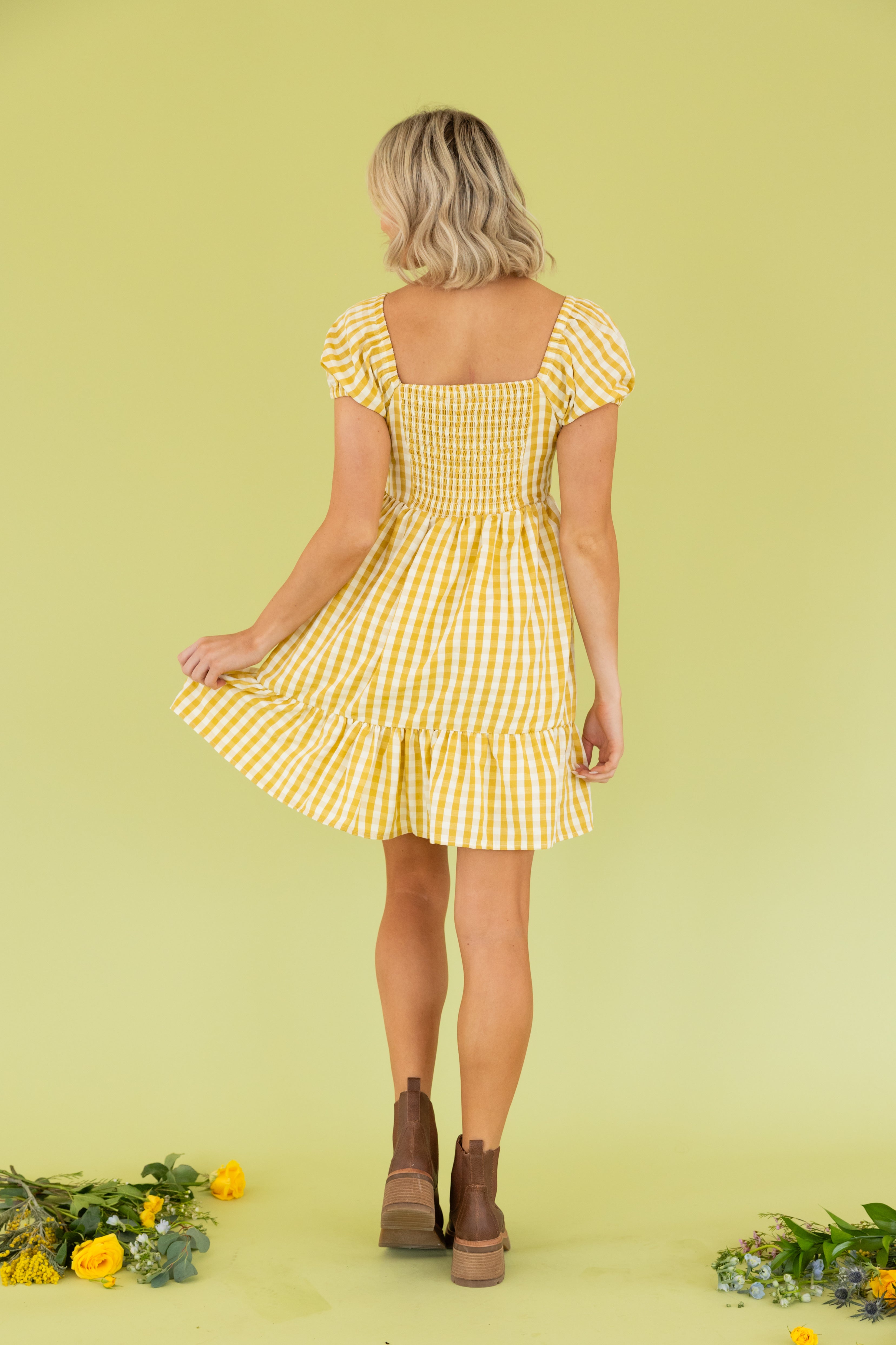 Model is wearing a mini yellow gingham dress.