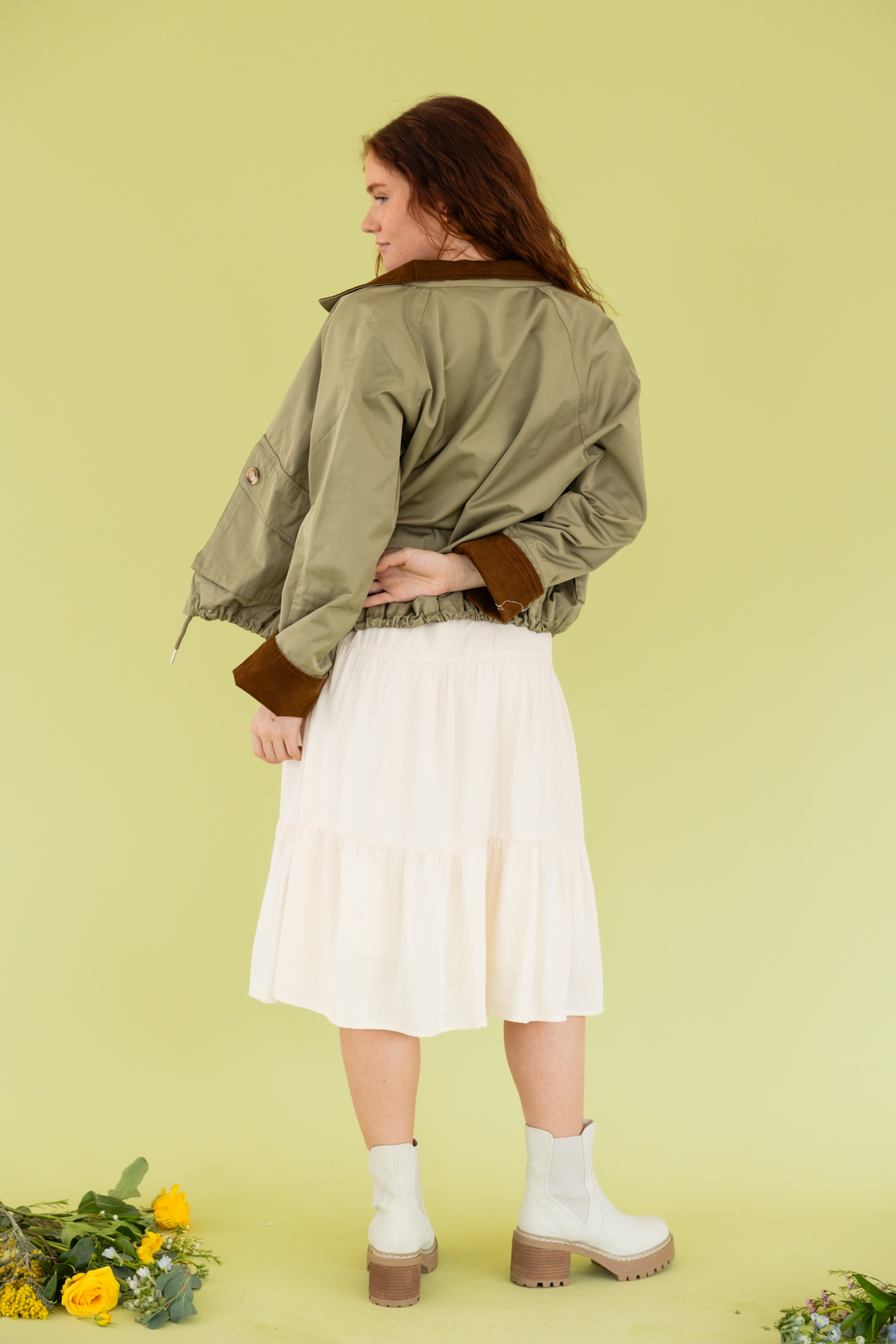 Model is wearing a green bomber jacket and midi dress.