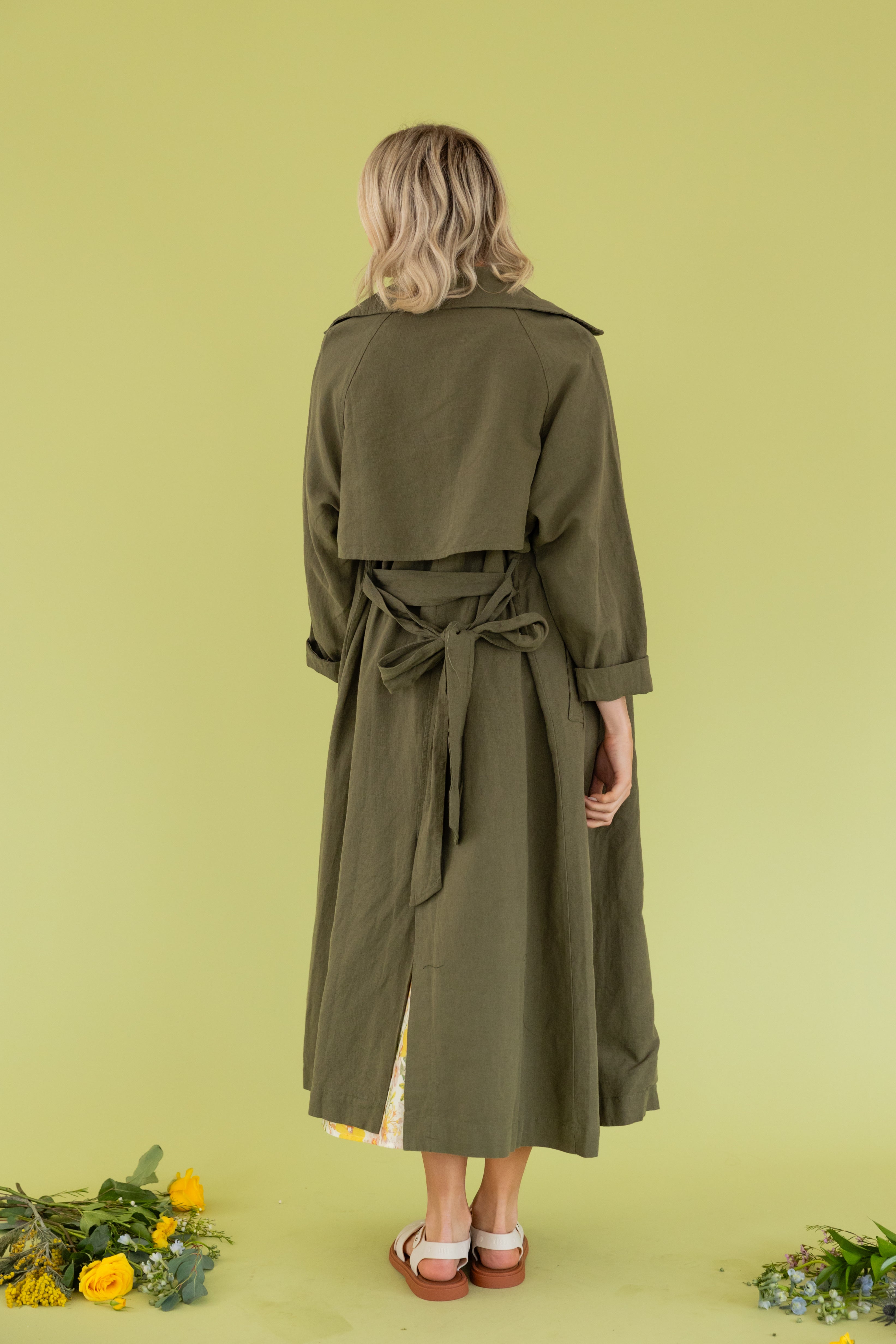 Model is wearing a green maxi trench coat.