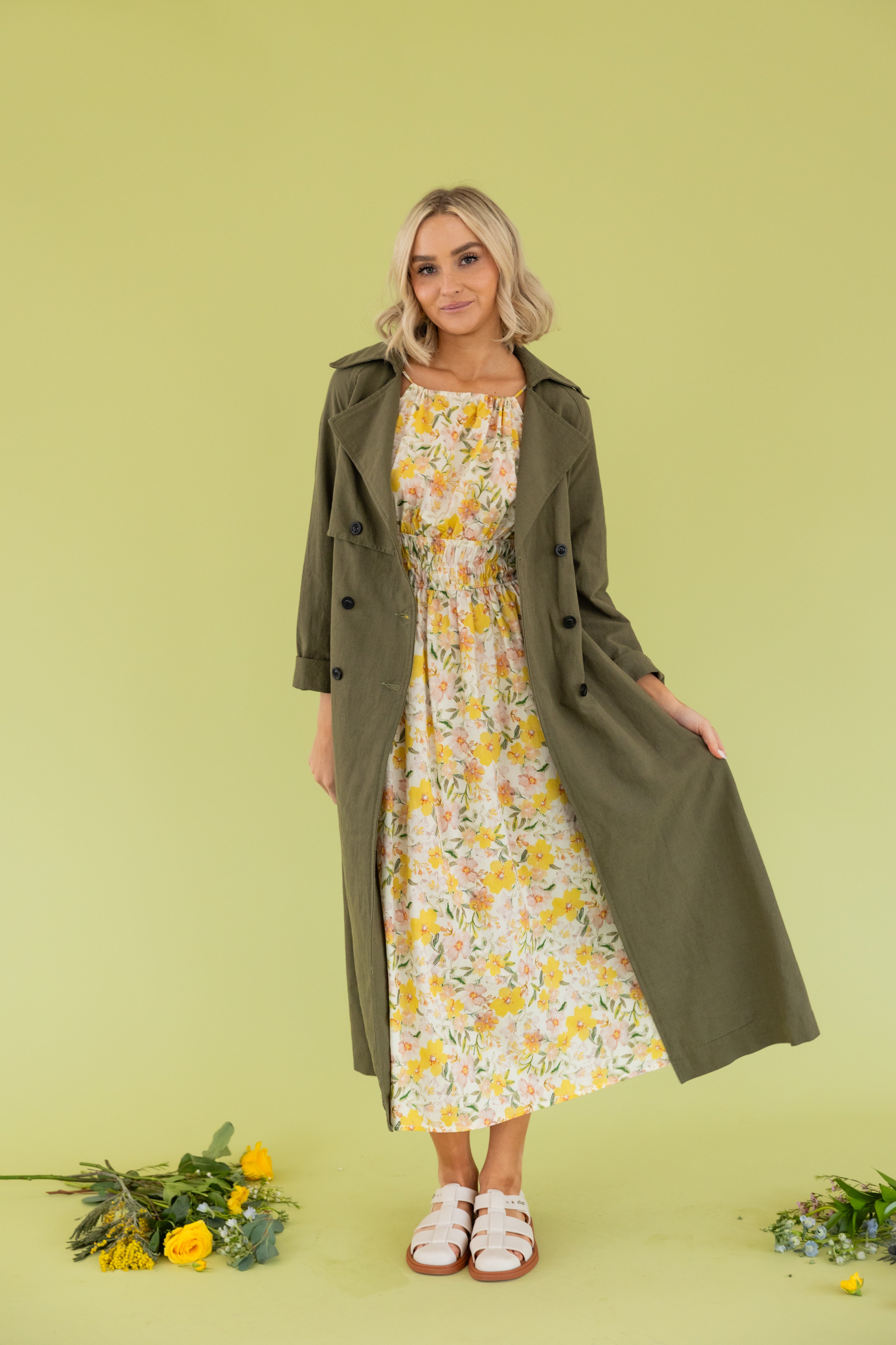 Model is wearing a green maxi trench coat.