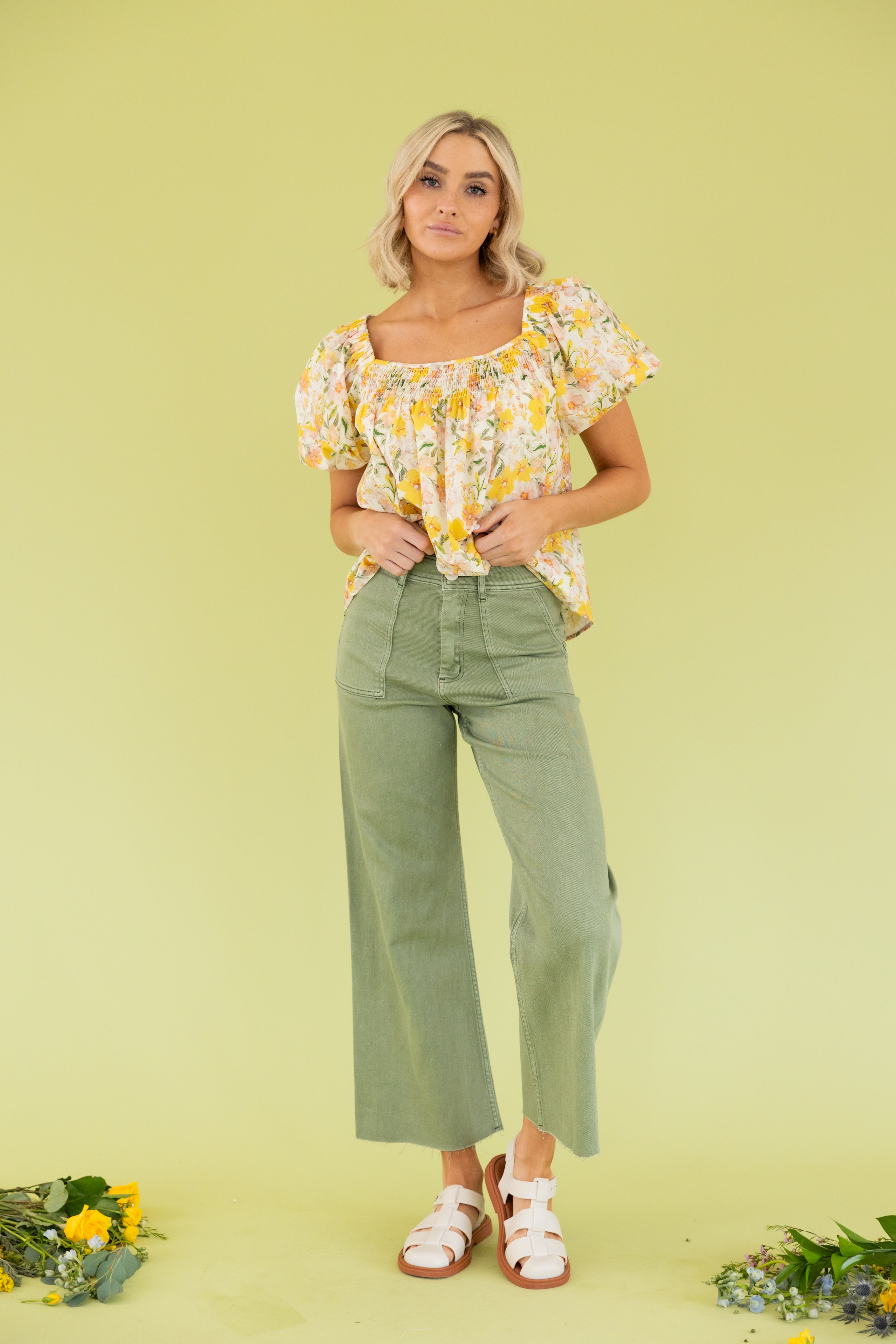 Model is wearing a yellow floral blouse and green wide leg pant. 