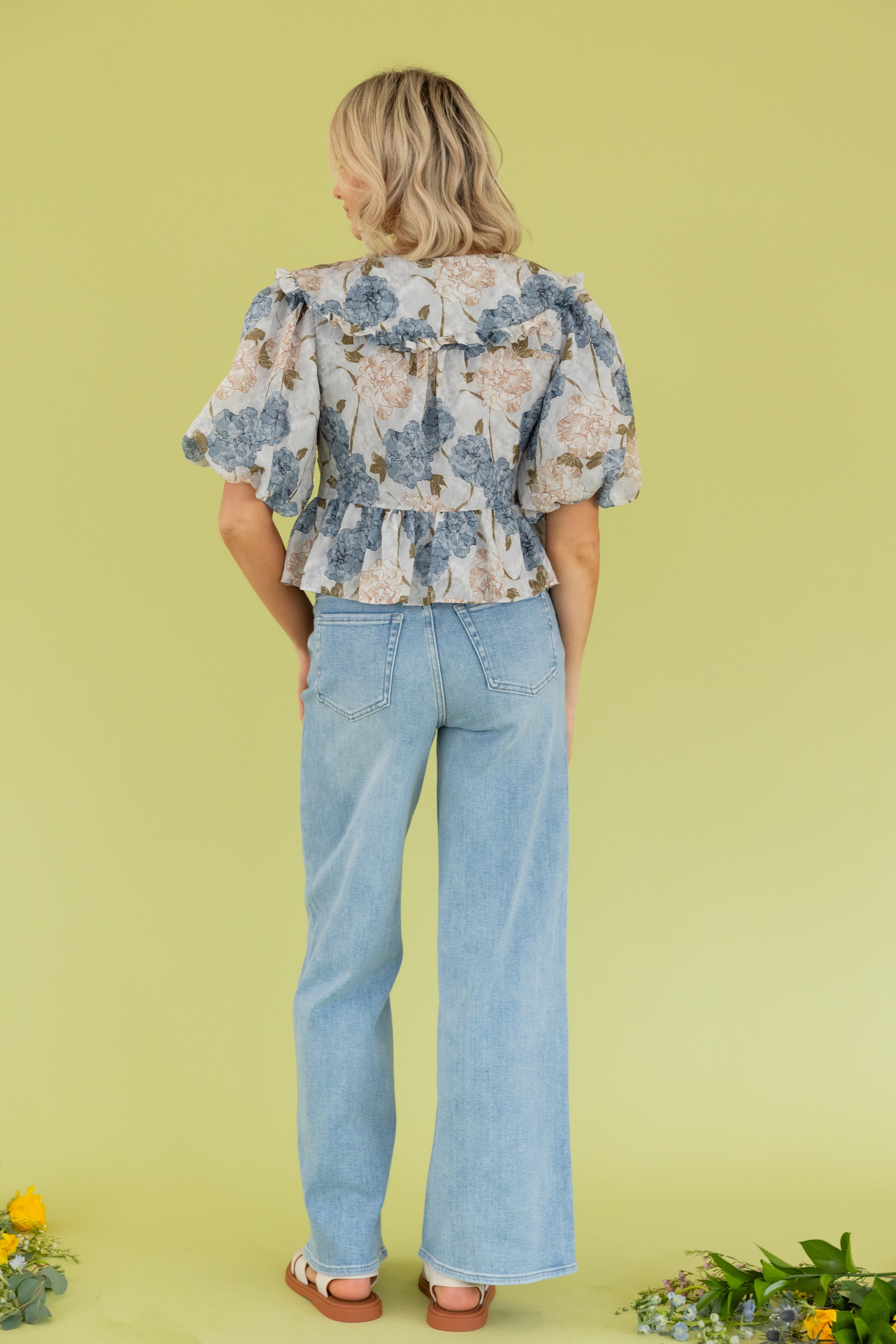 Model is wearing a floral blouse light blue jean.