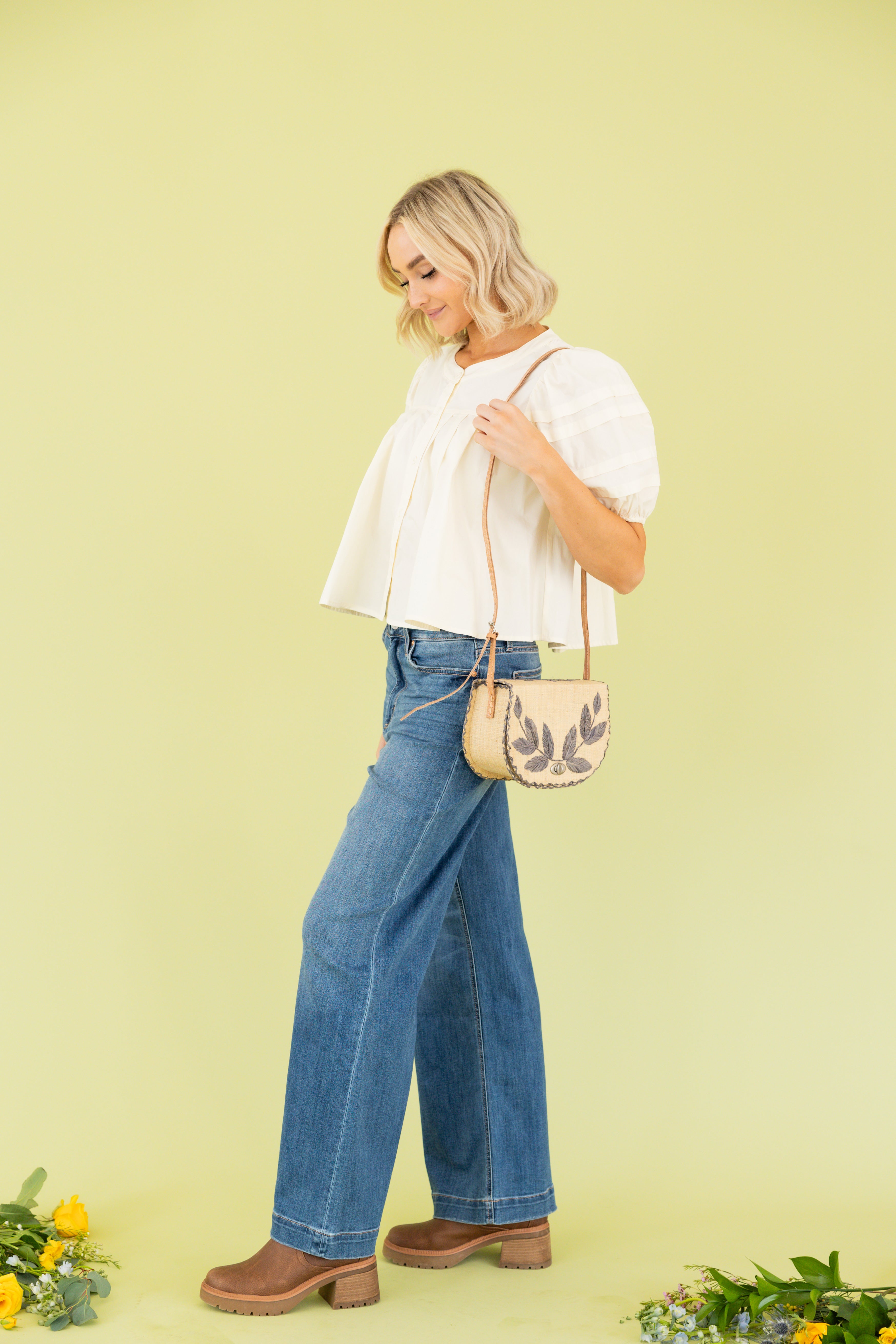 Model is wearing white blouse with wide leg dark wash jean 