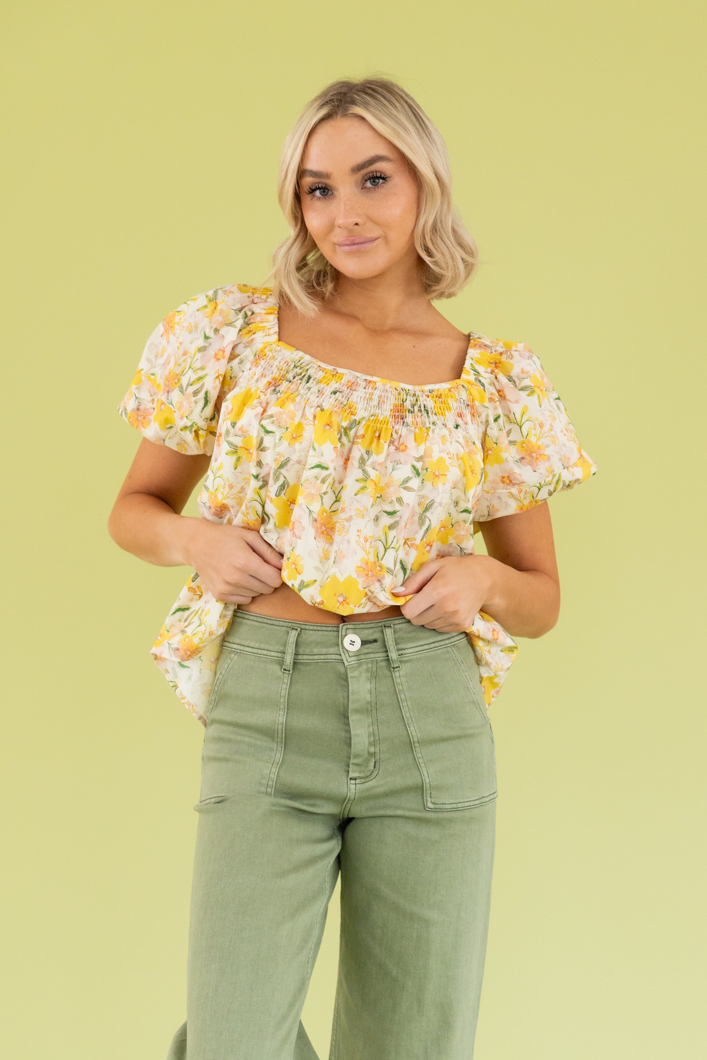 Model is wearing a yellow floral blouse and green wide leg pant.  