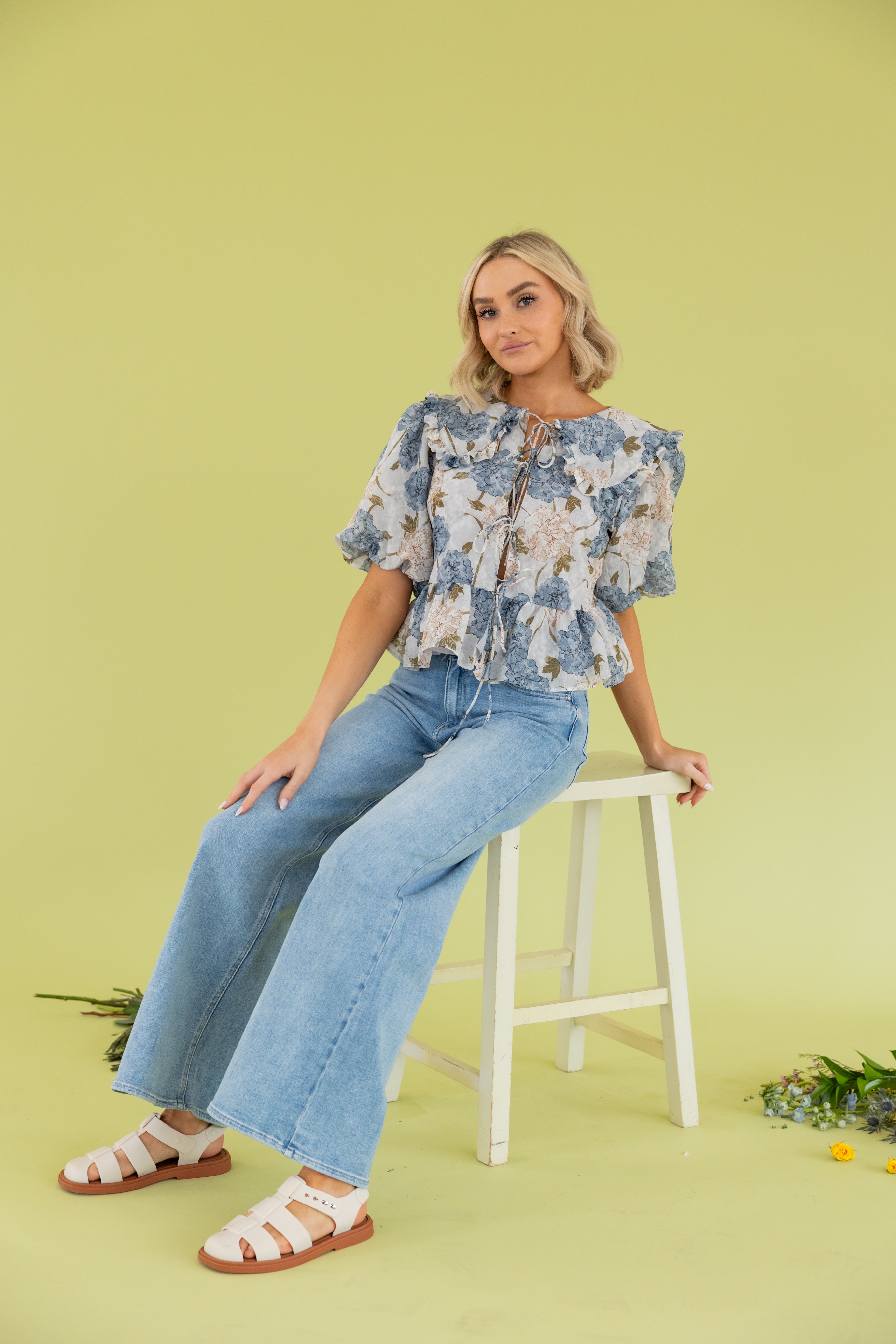 Model is wearing a floral blouse light blue jean.