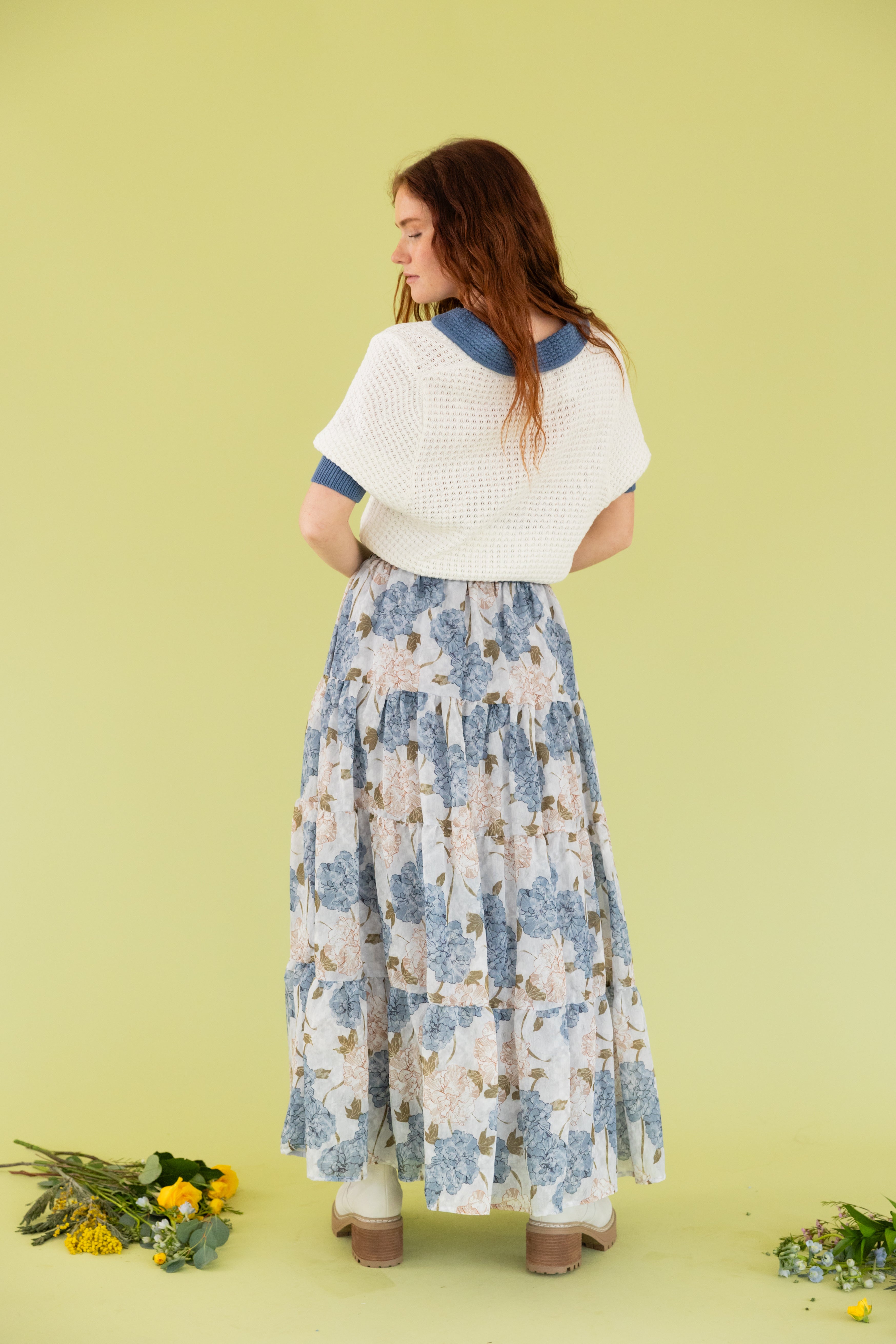 Model is wearing a knit sweater short sleeve top with midi floral blue and white skirt. 