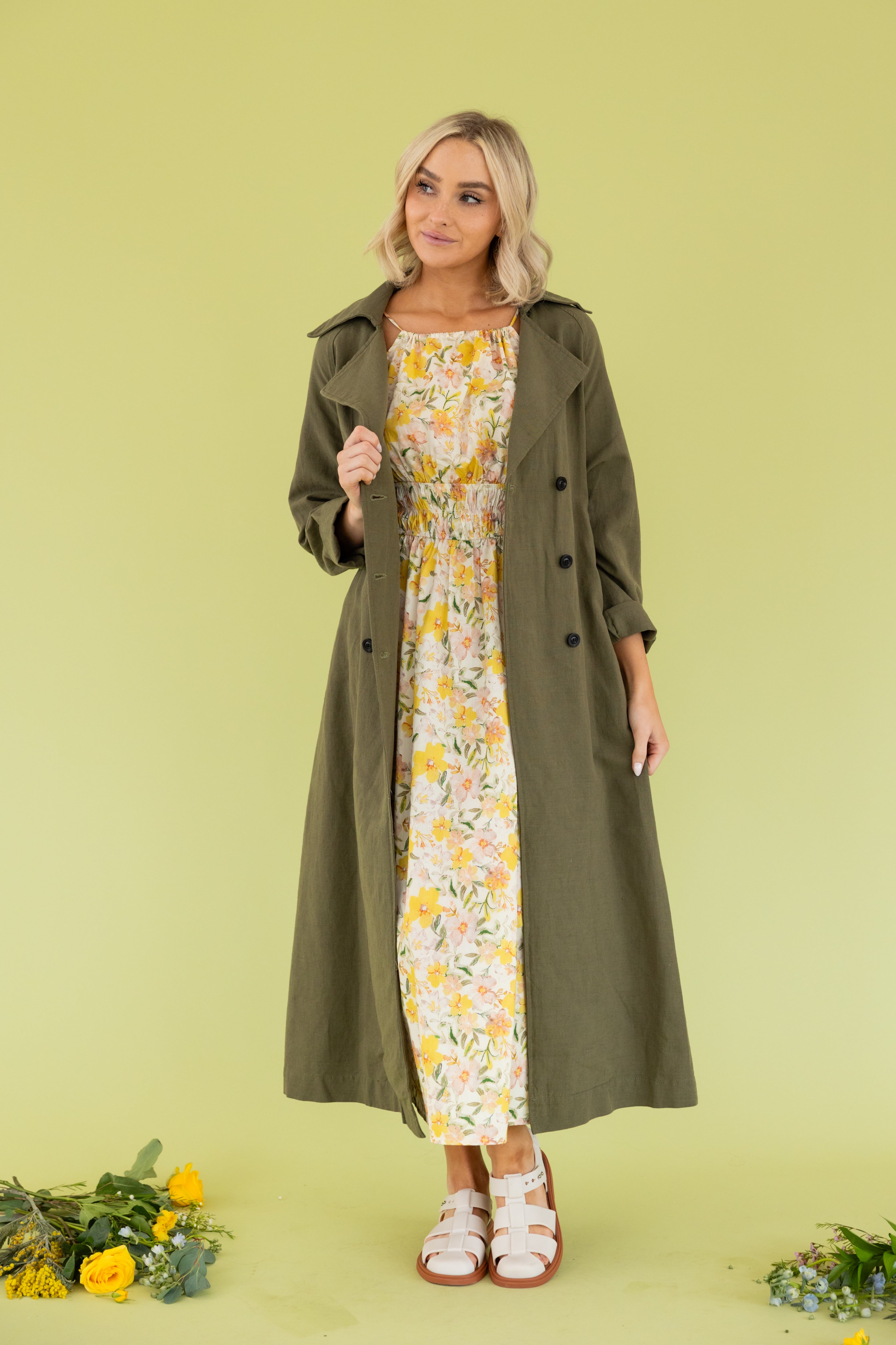 Model is wearing a green maxi trench coat.