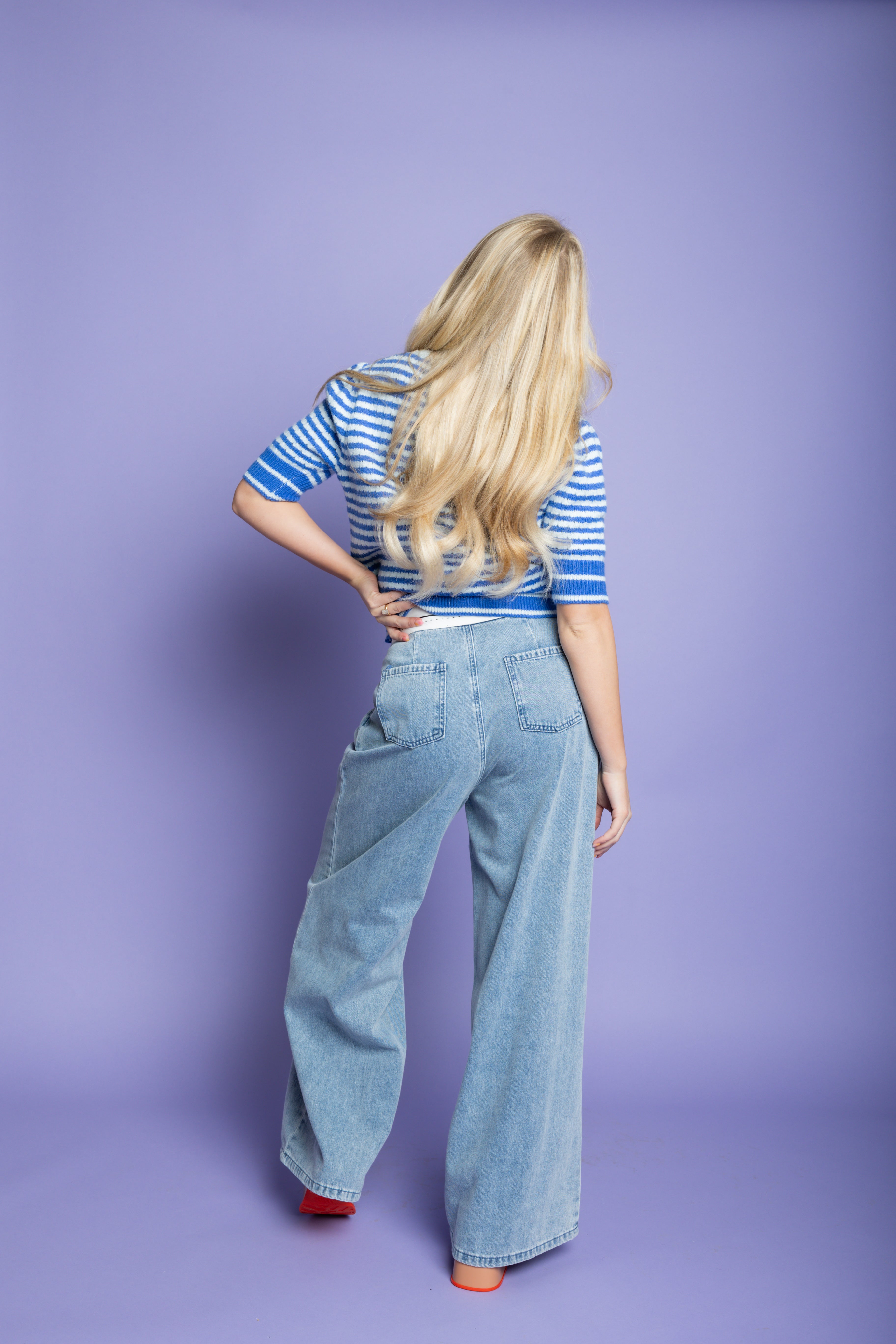 Model wearing blue striped sweater and blue oversized jeans