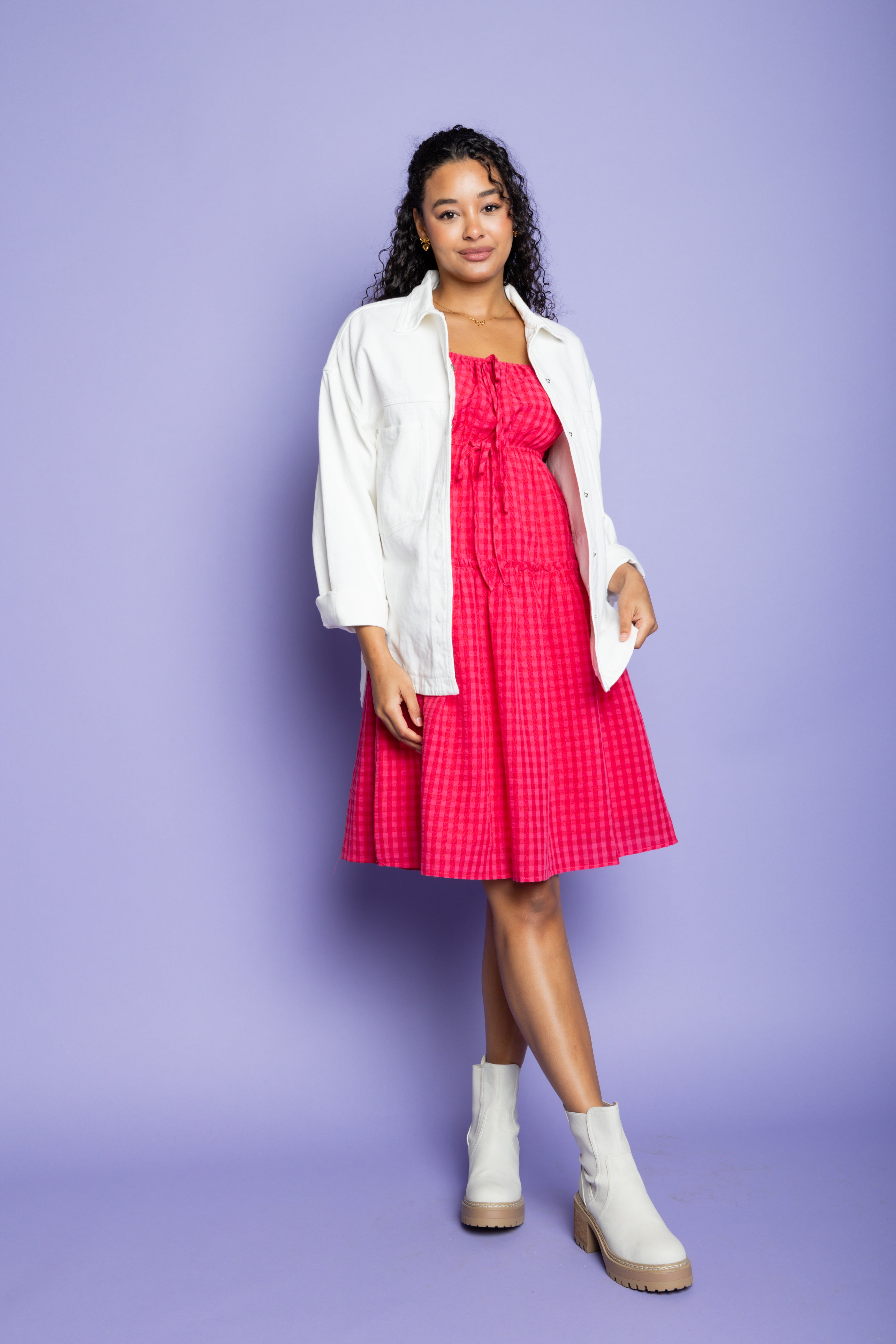 Model is wearing white collared jacket and pink dress.