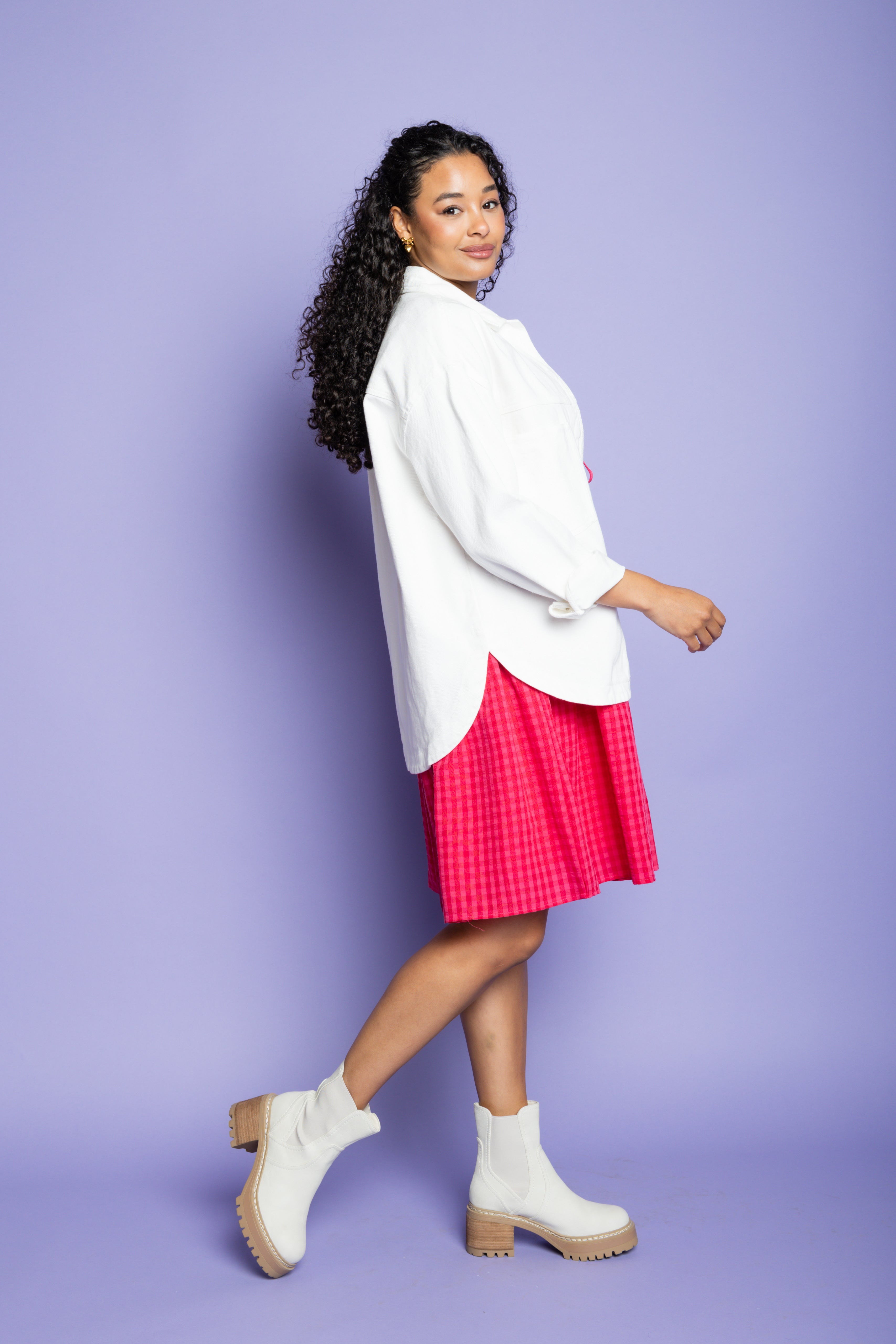 Model is wearing white collared jacket and pink dress.