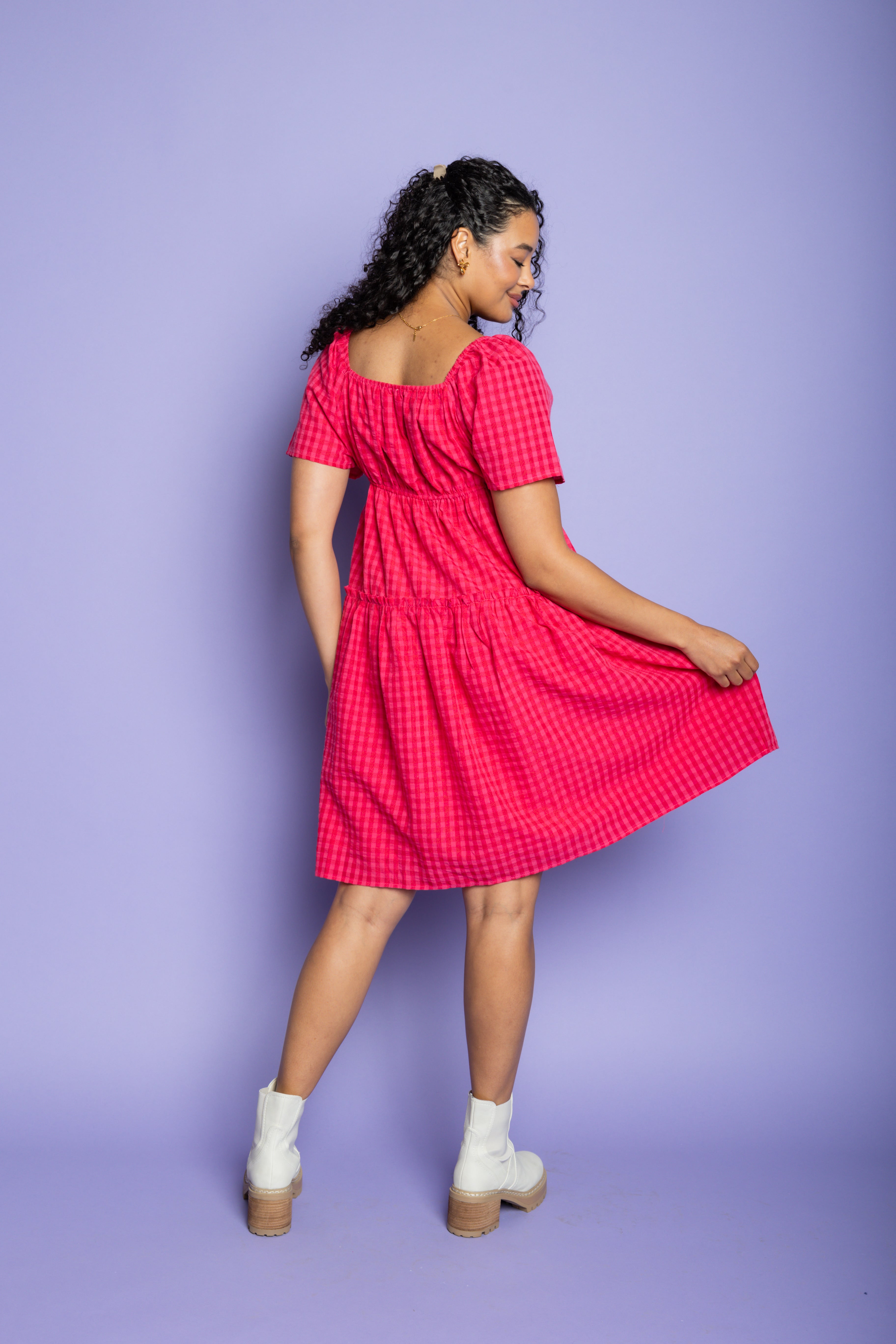 Model wearing pink gingham midi dress and white boots.