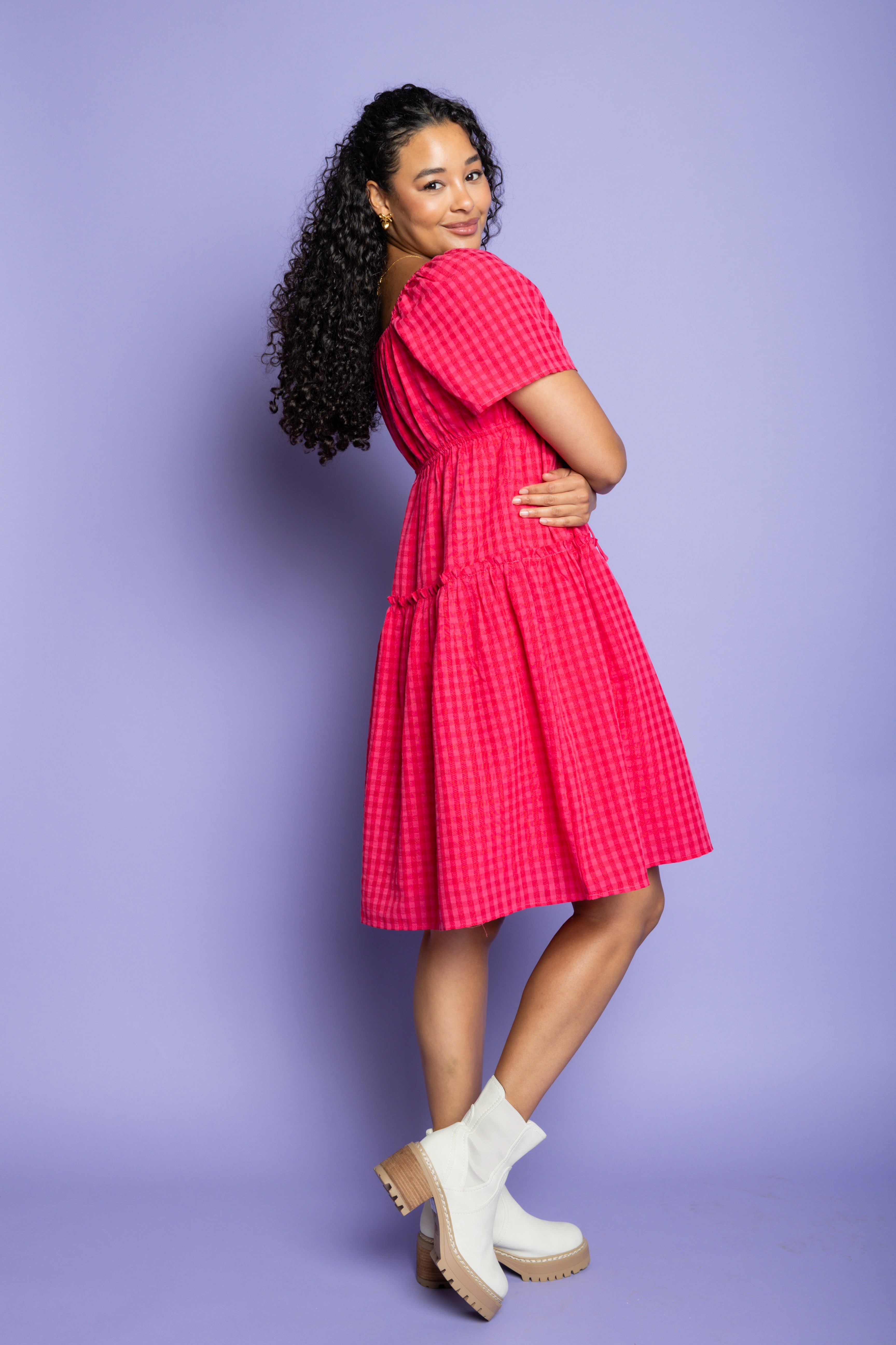 Model wearing pink gingham midi dress and white boots.