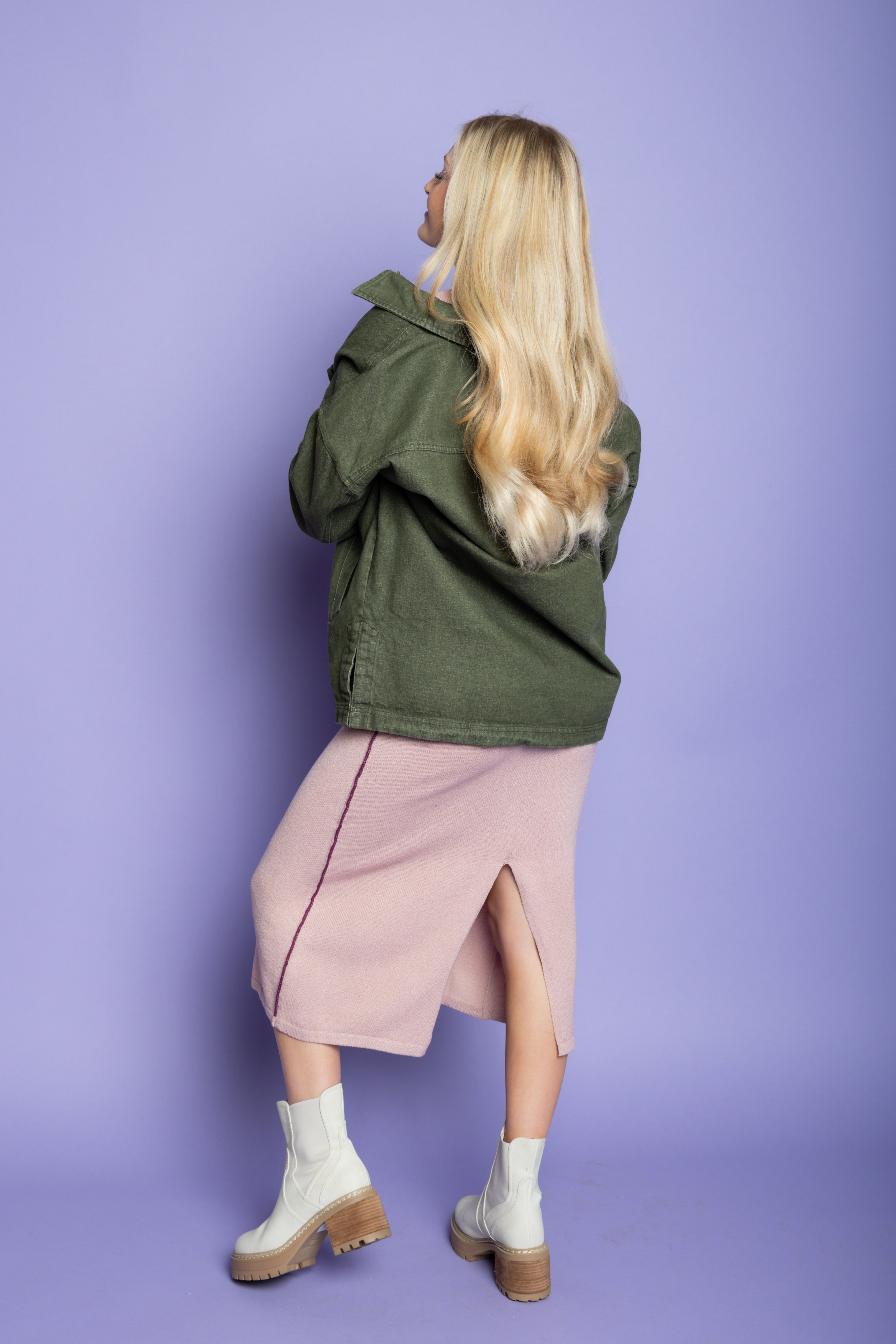 Model is wearing green utility jacket with pink matching skirt set. 