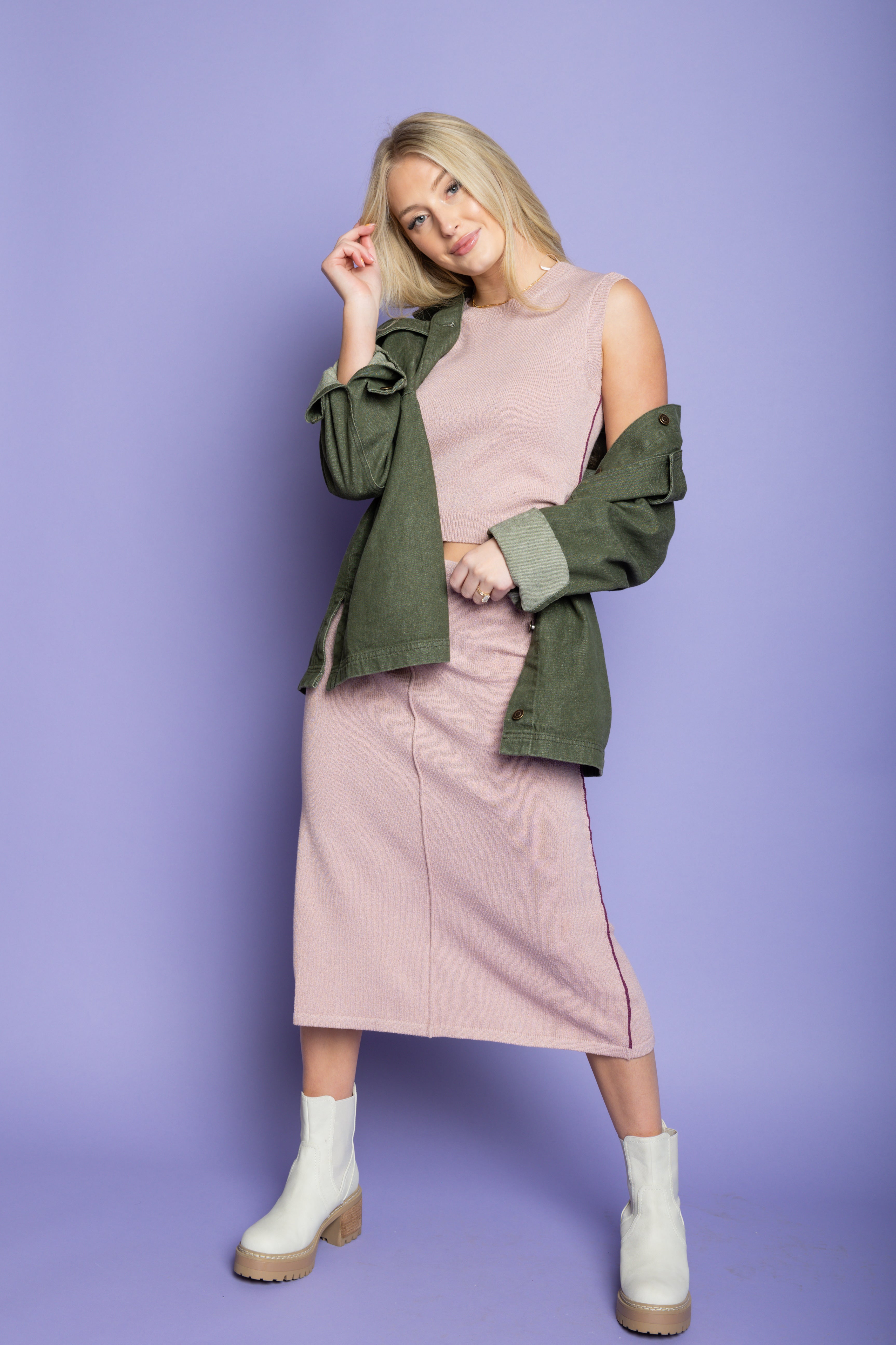 Model is wearing green utility jacket with pink matching skirt set. 