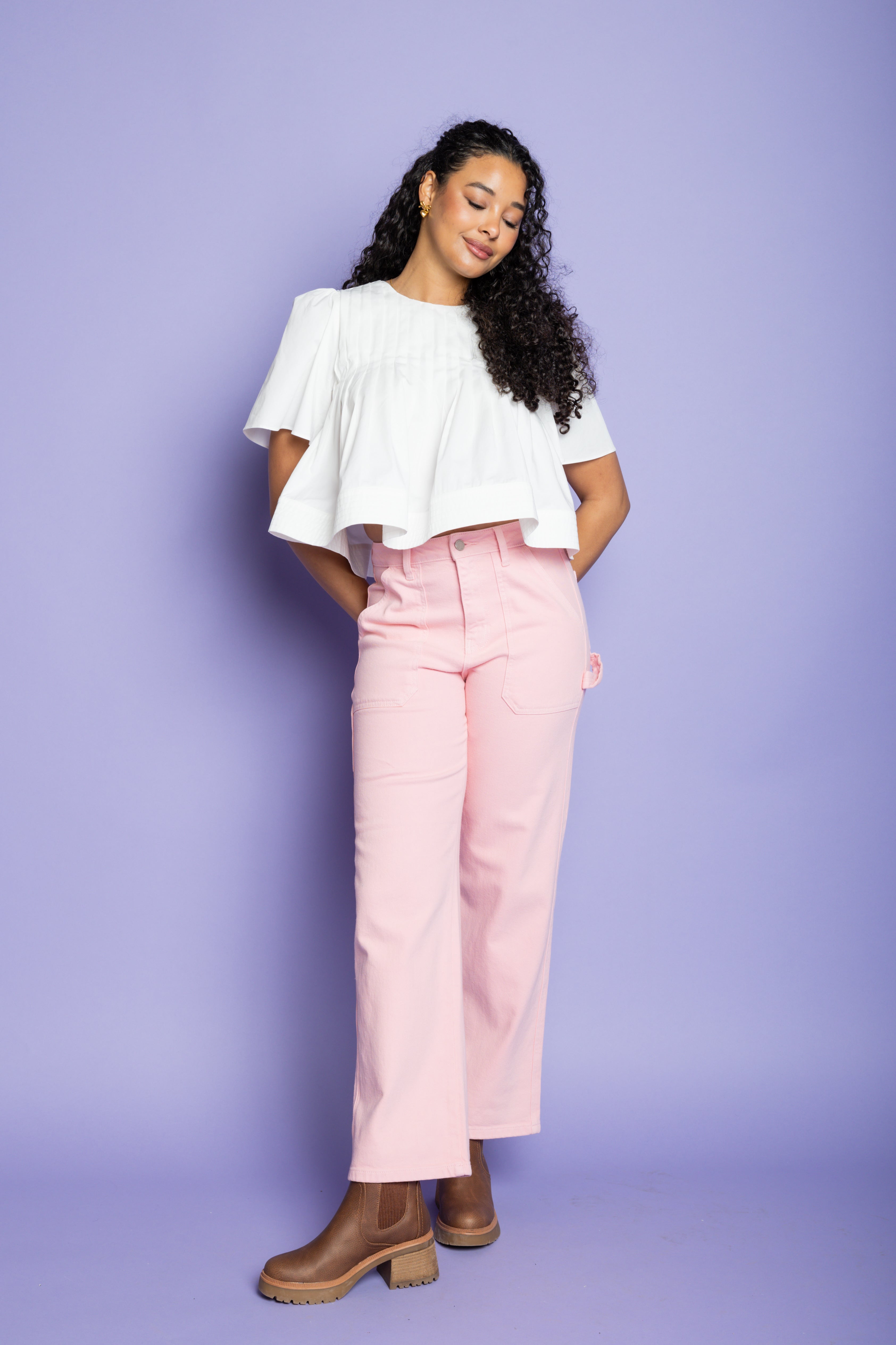 Model is wearing a white flowy short-sleeve blouse with pink straight leg pants.